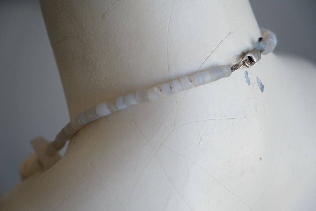 A white colored female form mannequin wears a necklace of white and blue botryoidal chalcedony