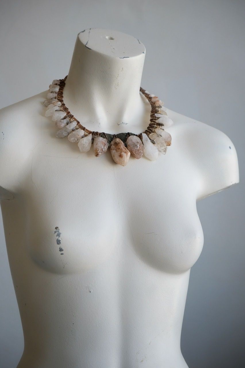 A white colored female form mannequin wears a sculptural necklace of rough quartz points and knotwork