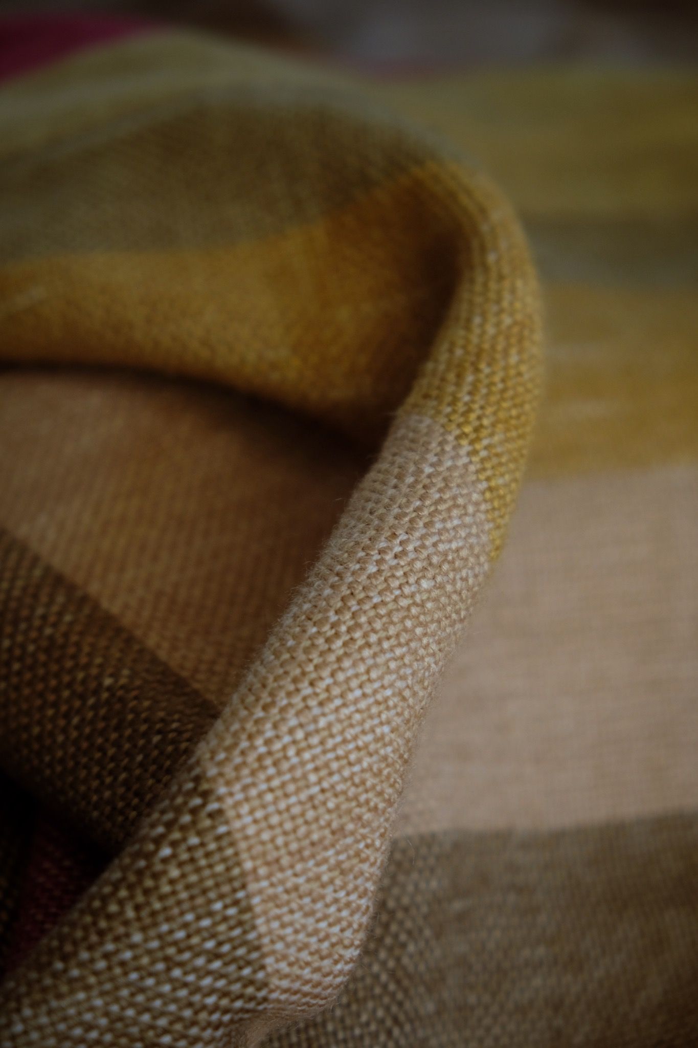 A detail of handwoven silk fabric in soft rainbow striped shades, naturally dyed