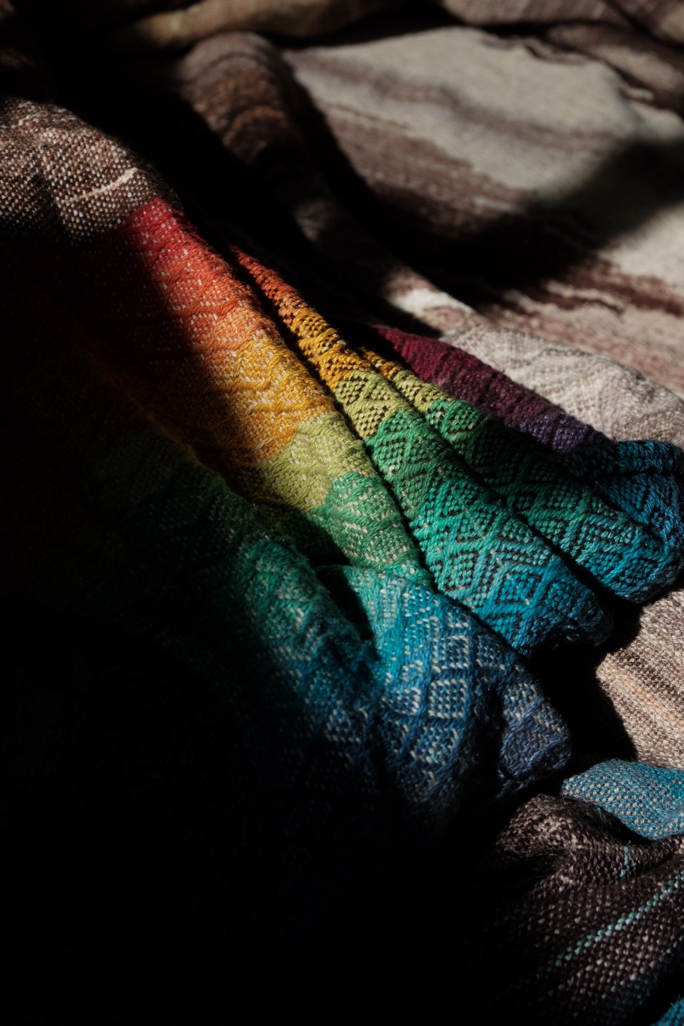 Handwoven fabric with a diamond pattern in brown, cream, white and rainbow colors