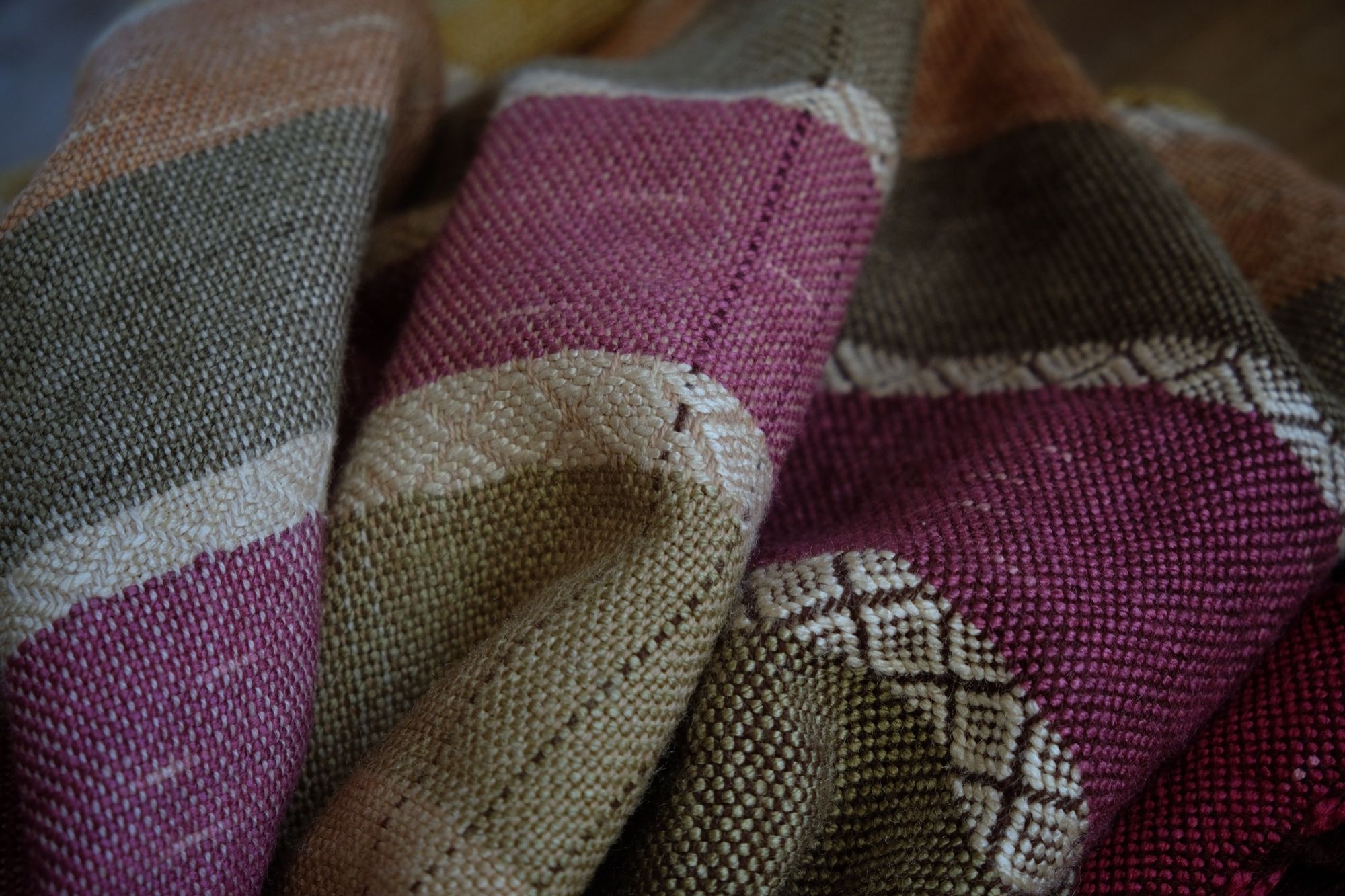 A detail of handwoven silk fabric in soft rainbow striped shades, naturally dyed