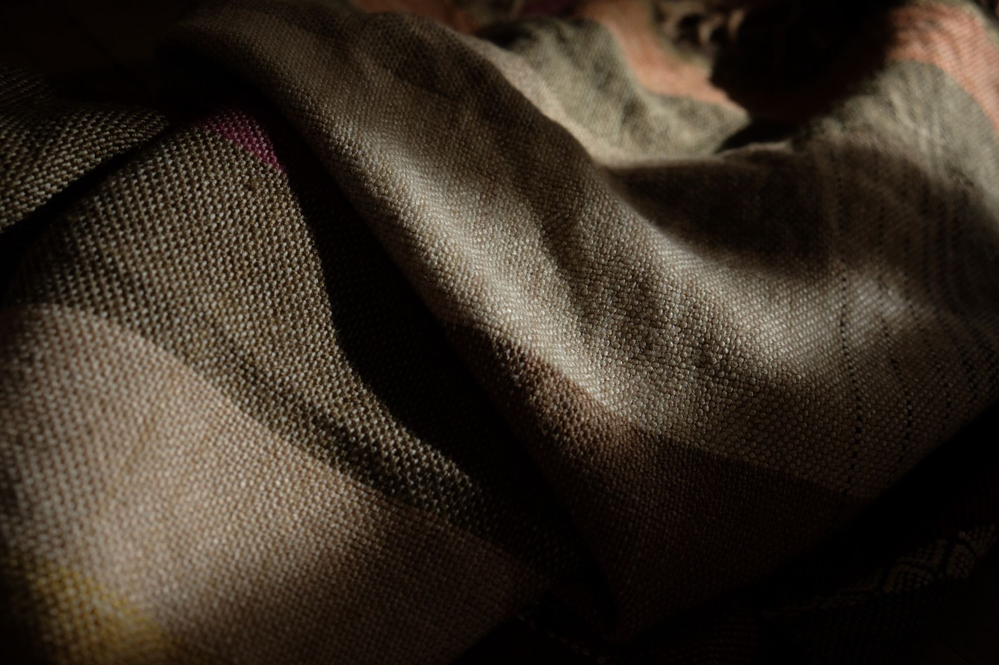 A detail of handwoven silk fabric in soft rainbow striped shades, naturally dyed