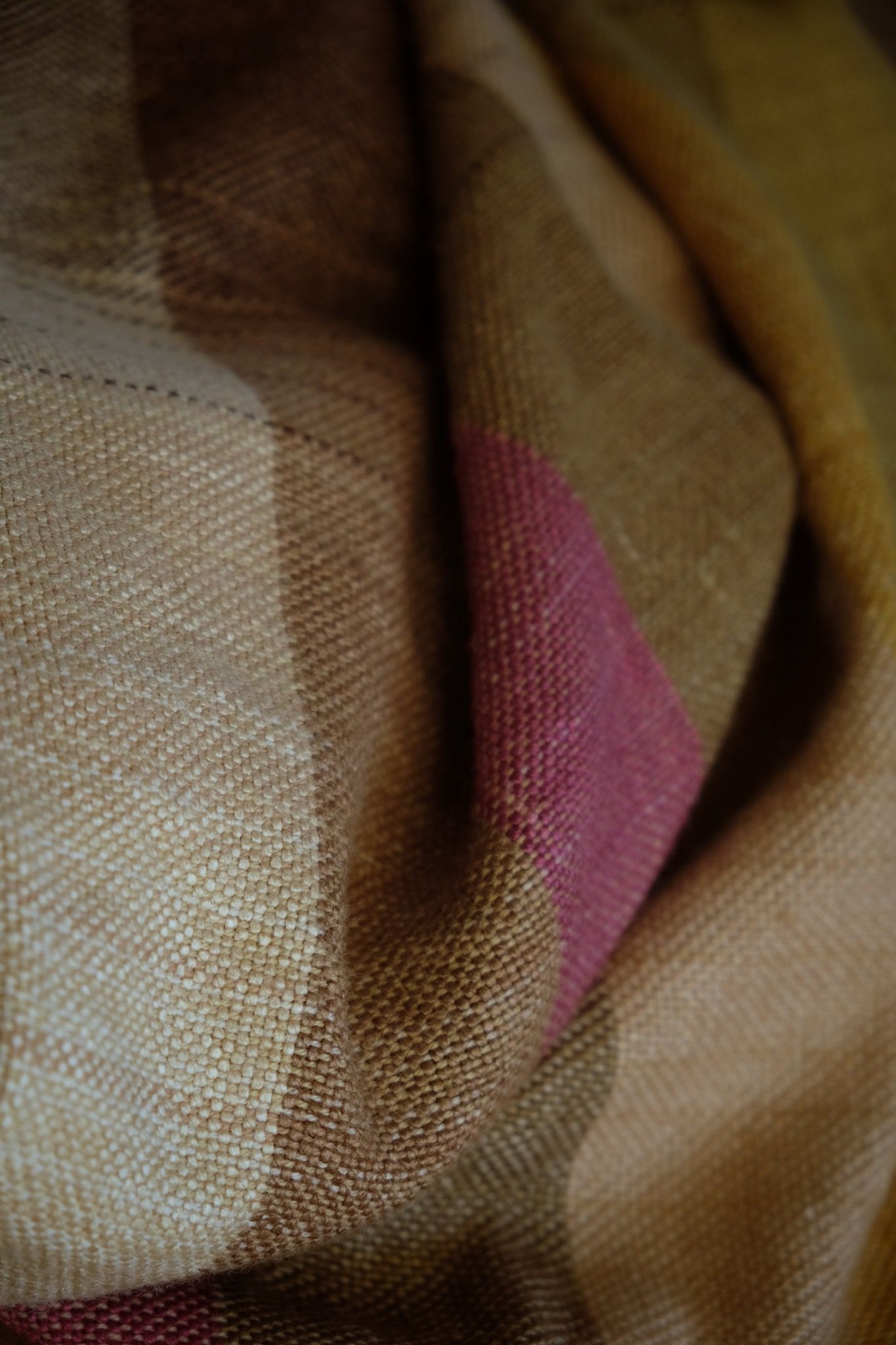 A detail of handwoven silk fabric in soft rainbow striped shades, naturally dyed