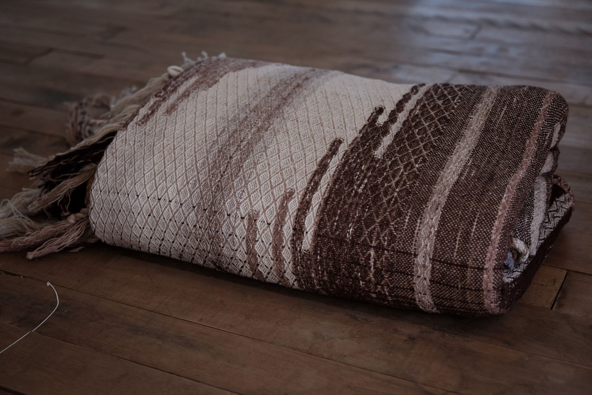 Handwoven fabric with a diamond pattern in brown, cream, white and rainbow colors
