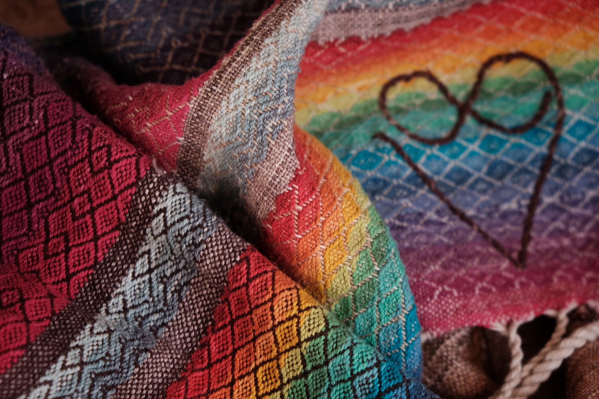 Handwoven fabric with a diamond pattern in brown, cream, white and rainbow colors with a heart detail