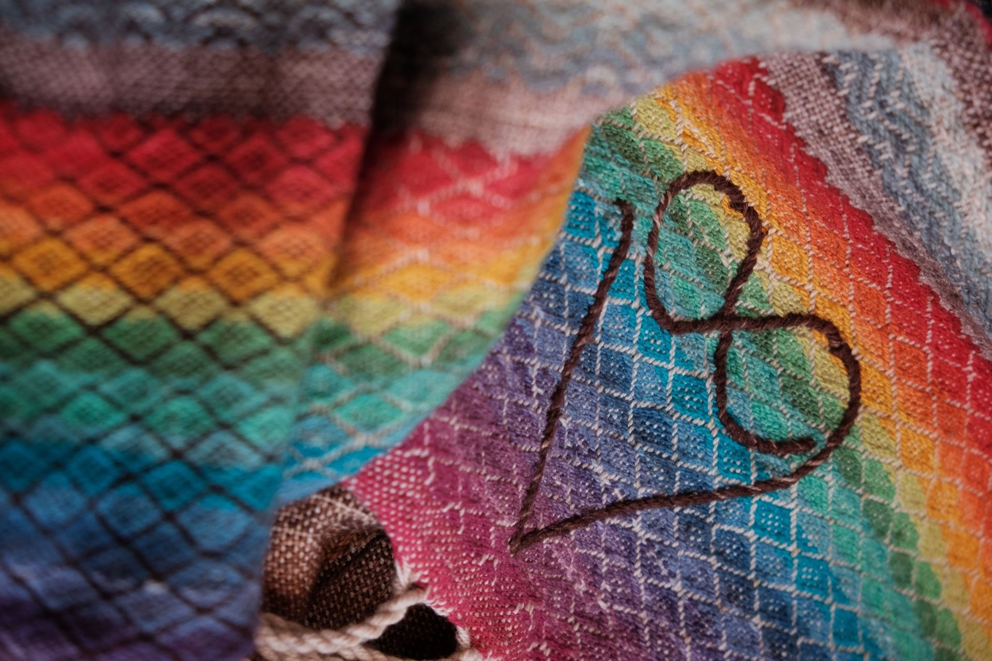 Detail of handwoven highly textured diamond pattern raw silk fabric with a heart and rainbow