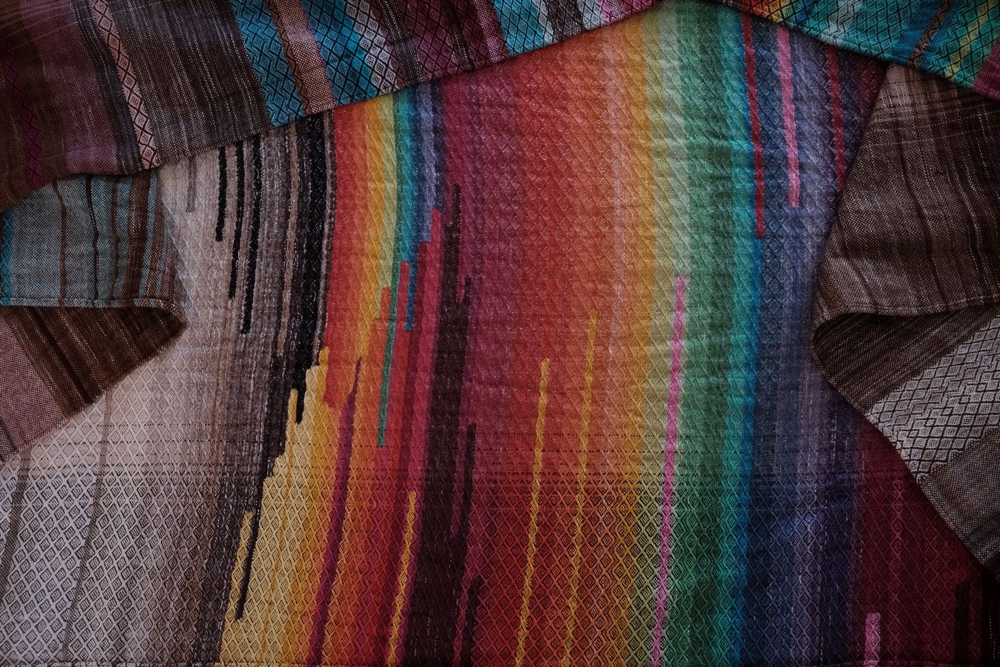Detail of handwoven highly textured diamond pattern raw silk fabric in rainbow and black