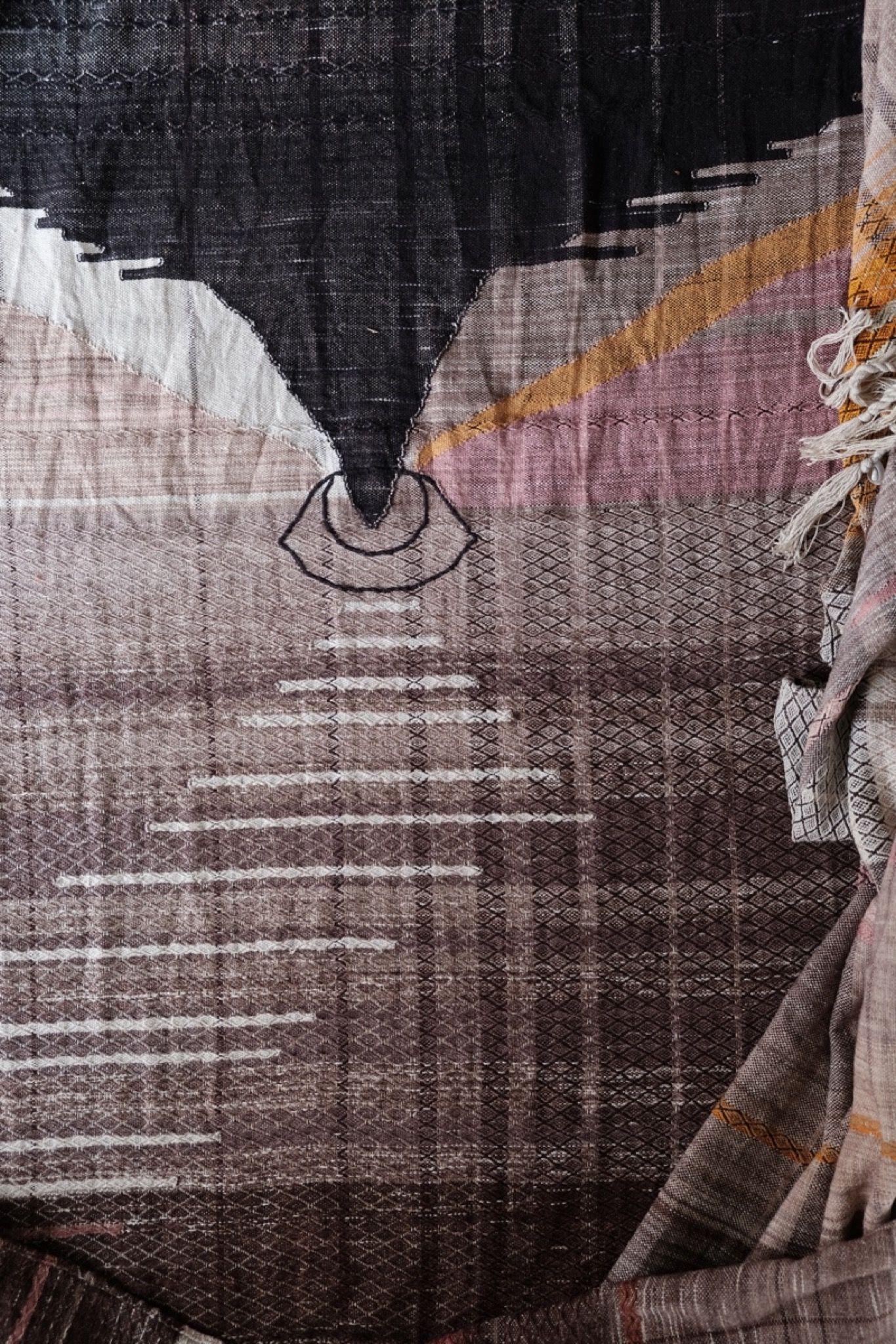 Detail of handwoven highly textured diamond pattern raw silk fabric with an eye radiating geometric shapes