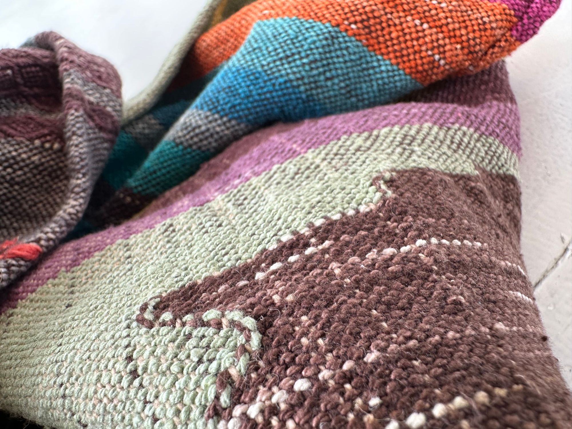 A detail of raw silk handwoven fabric in a rainbow of hand dyed colors with circular moon-like details 