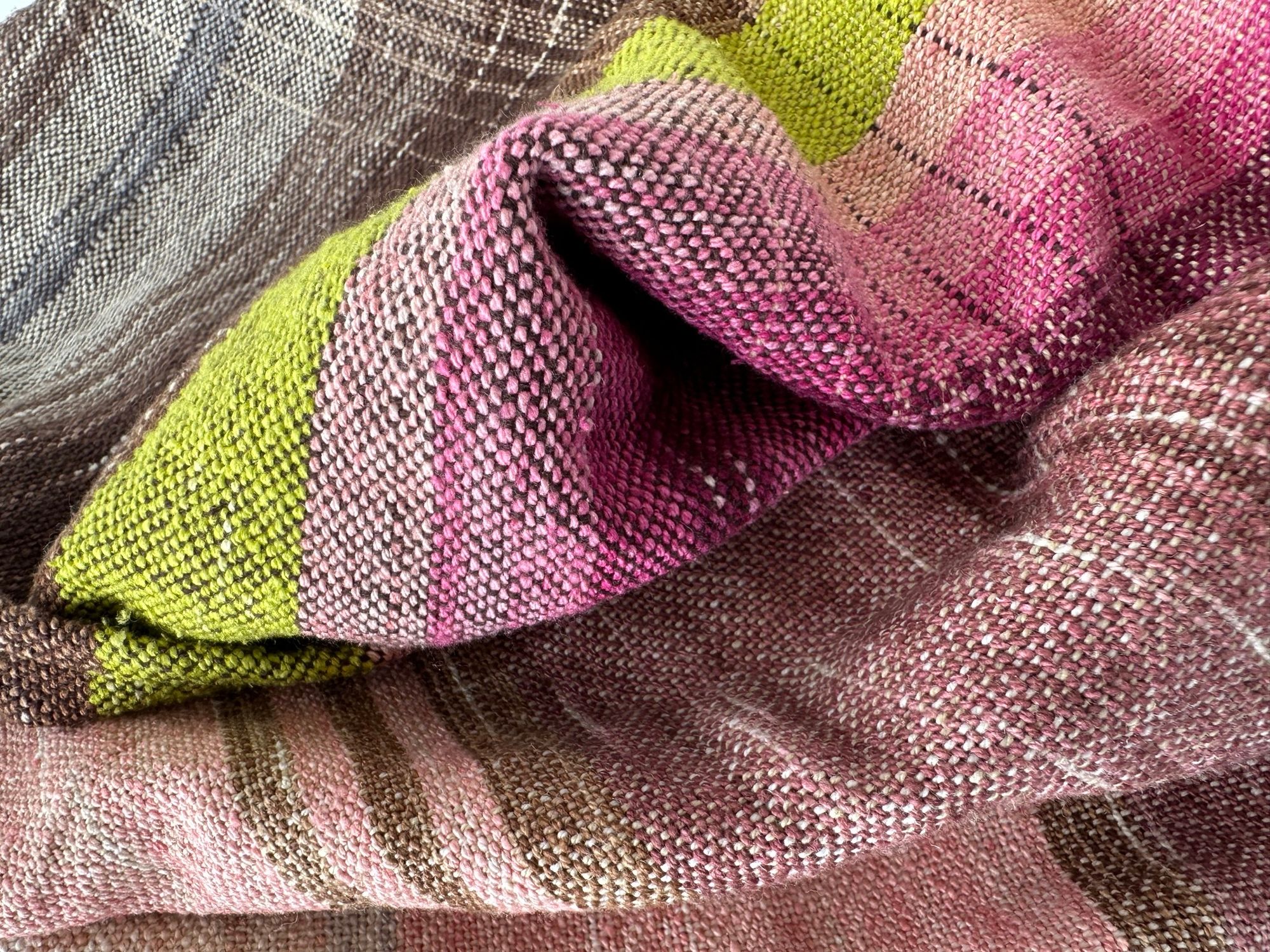 A detail of raw silk handwoven fabric in a rainbow of hand dyed colors with circular moon-like details 