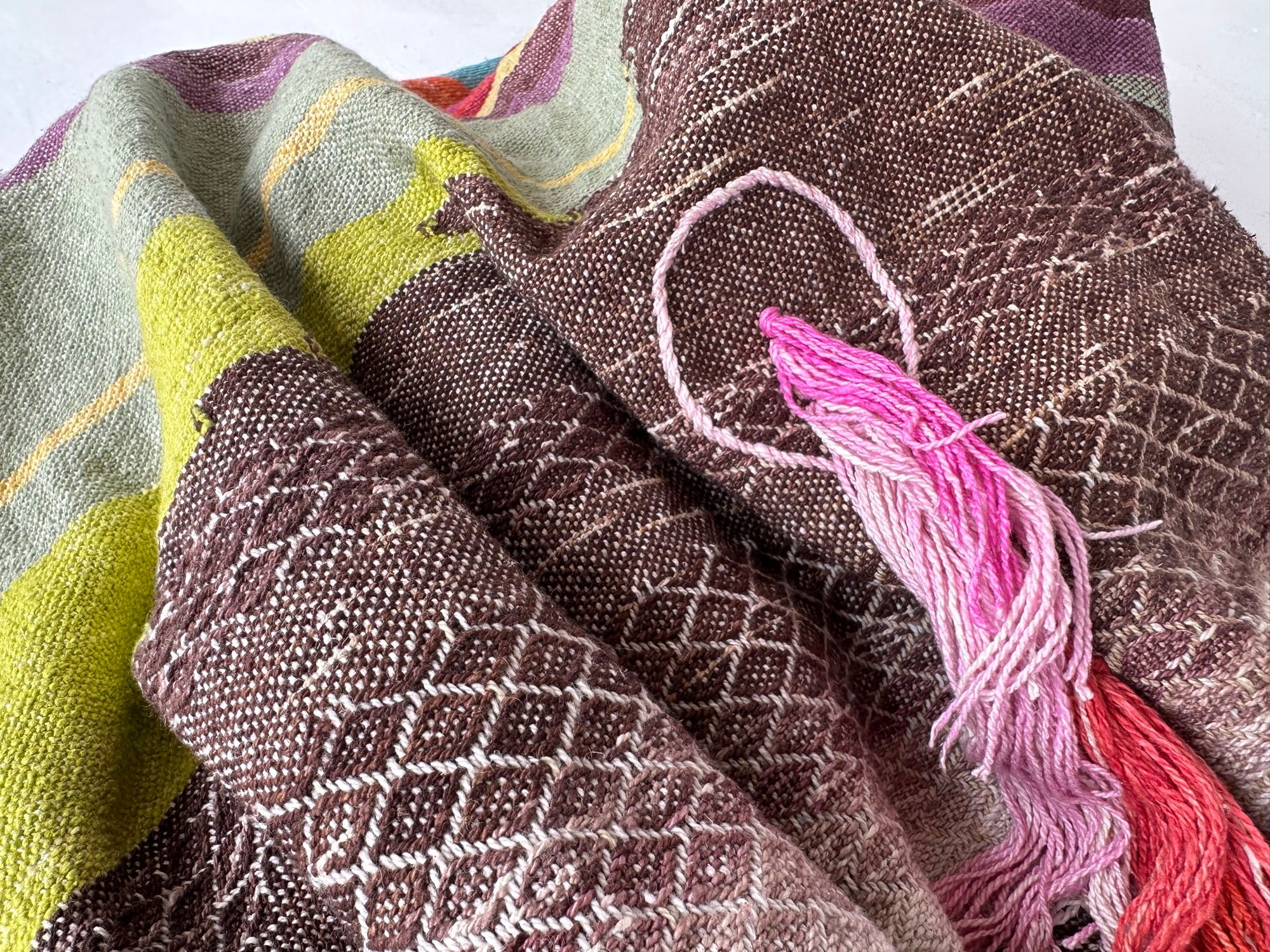 A detail of raw silk handwoven fabric in a rainbow of hand dyed colors with circular moon-like details 