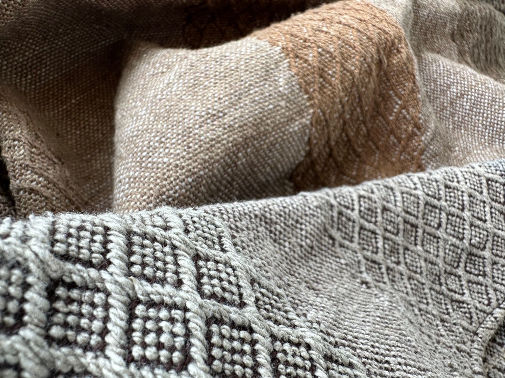A detail of handwoven softly graded grey to white to brown diamond pattern raw silk fabric