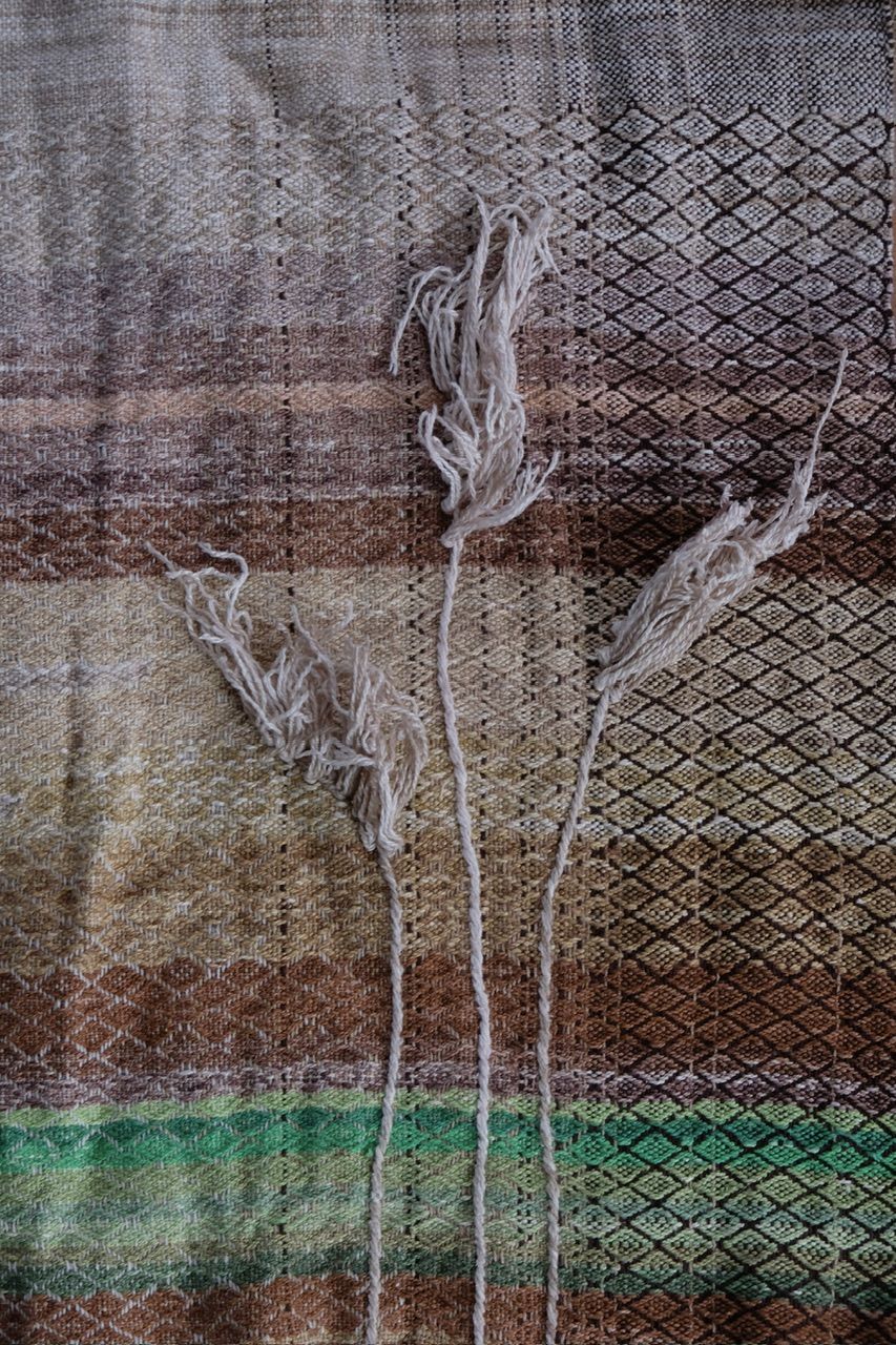 details of woven grass on handwoven raw silk fabric with a textured diamond pattern in shades of blue, warm sunset and white-straw-brown