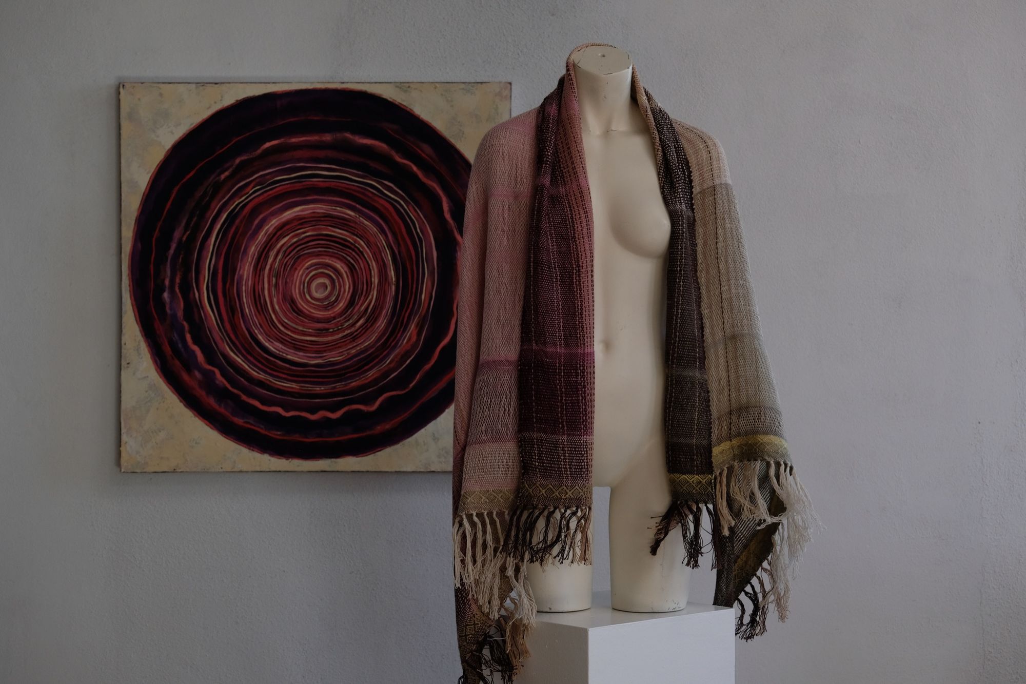 Handwoven organic cotton-linen, tussah silk and silk-merino scarf naturally dyed shades of pink, brown and green on a white mannequin in a white gallery space