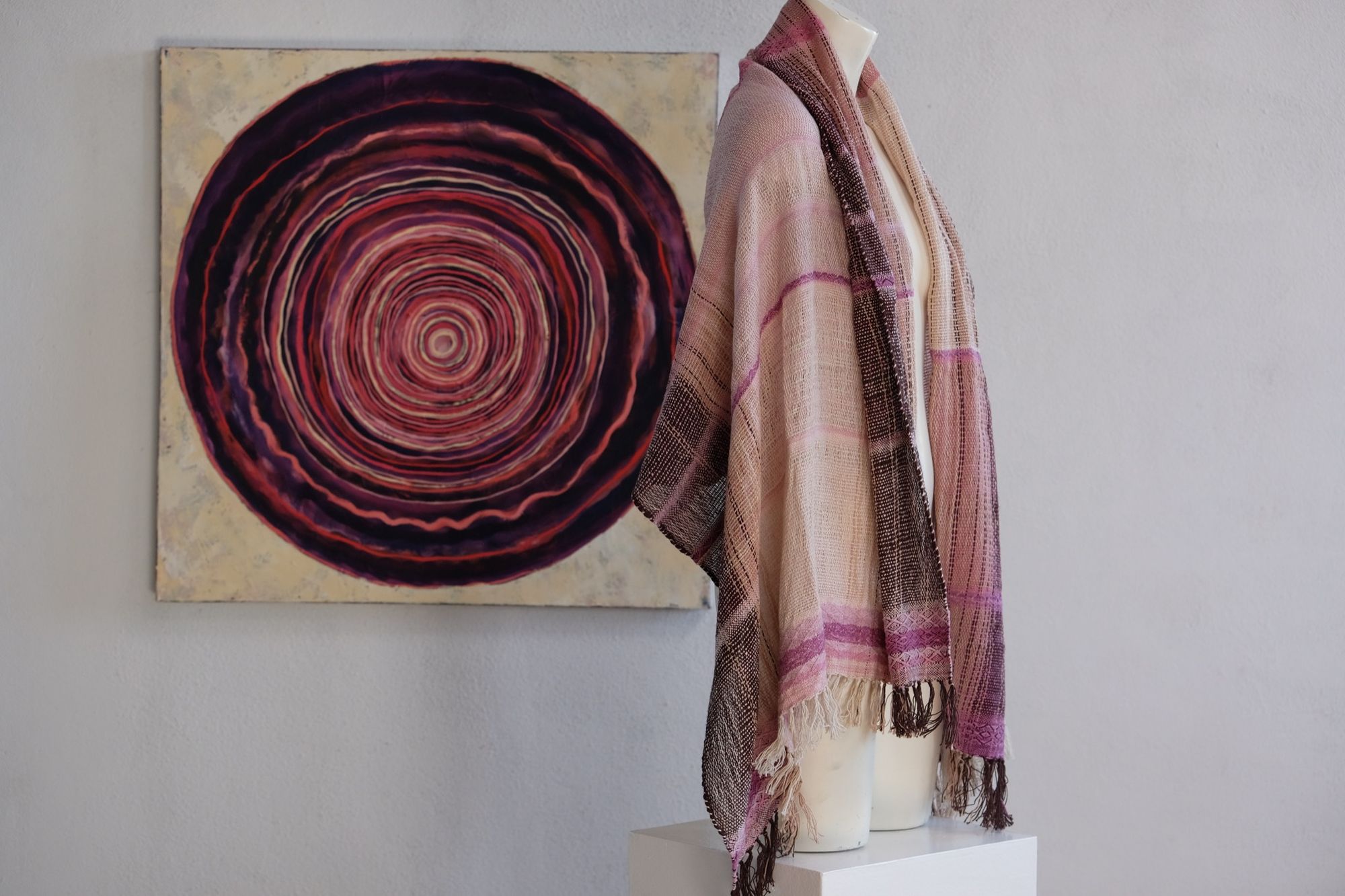 Handwoven scarf naturally dyed shades of pink and fuchsia on a white mannequin in a white gallery space