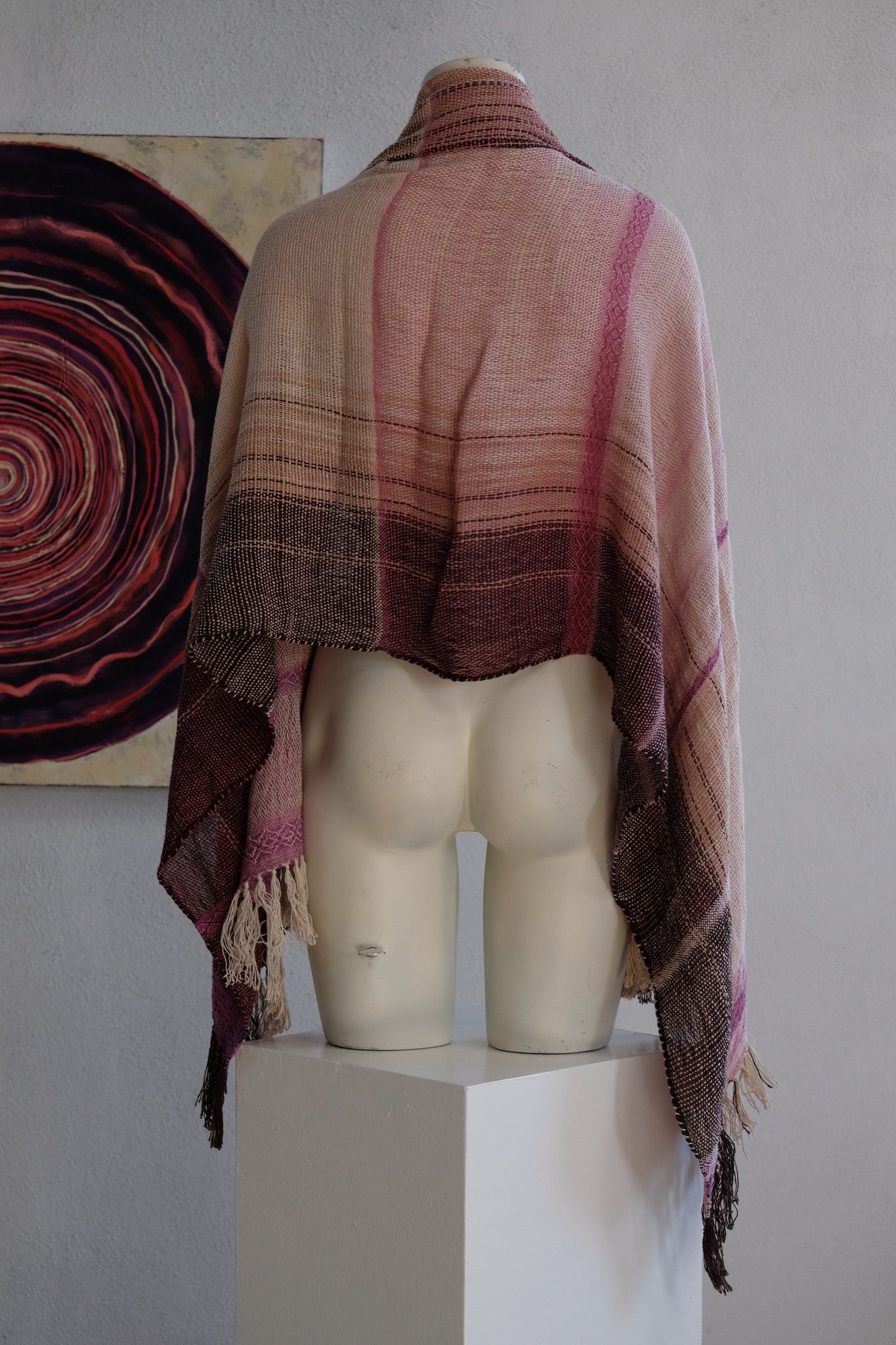 Handwoven scarf naturally dyed shades of pink and fuchsia on a white mannequin in a white gallery space