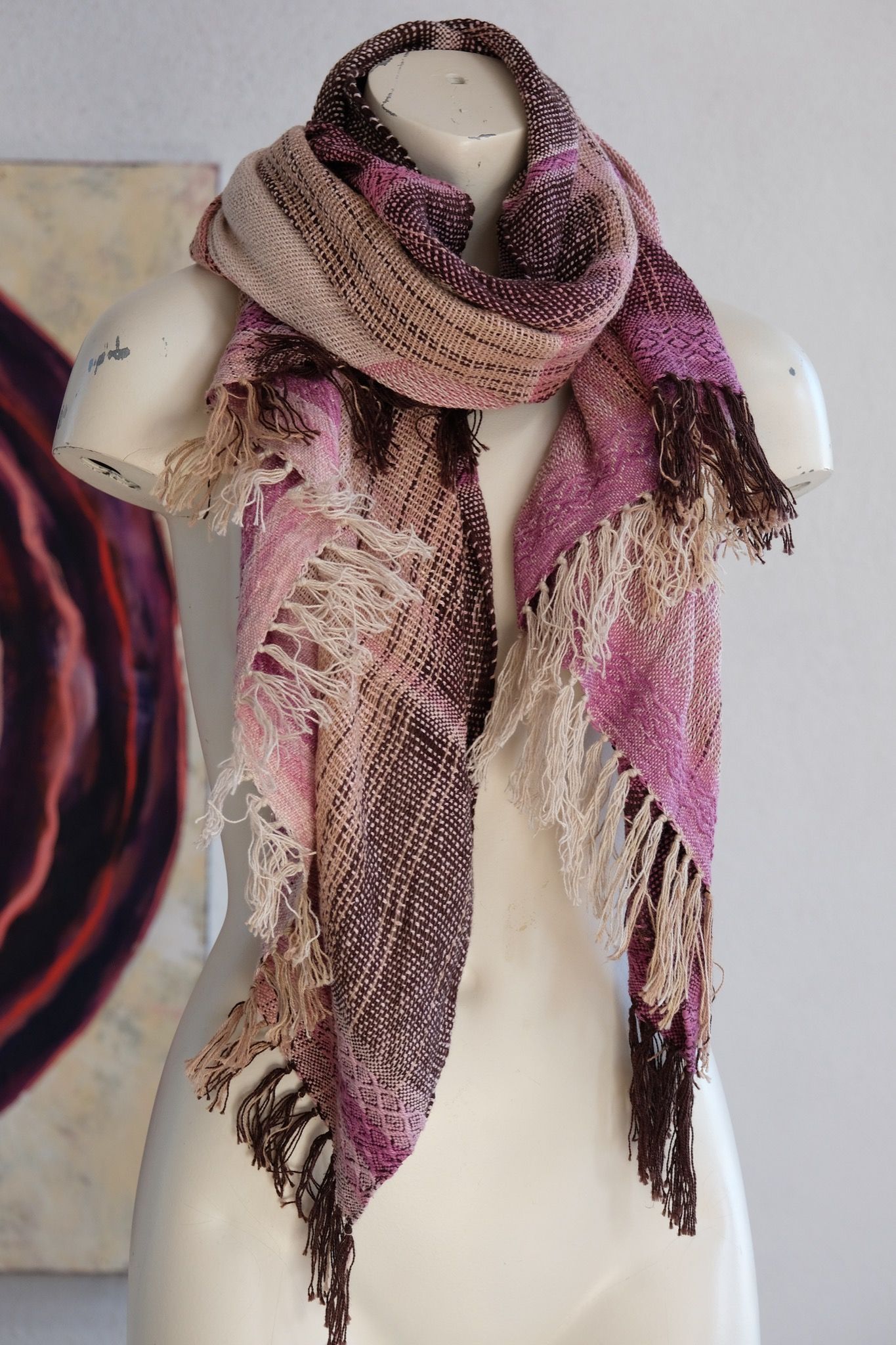 Handwoven scarf naturally dyed shades of pink and fuchsia on a white mannequin in a white gallery space