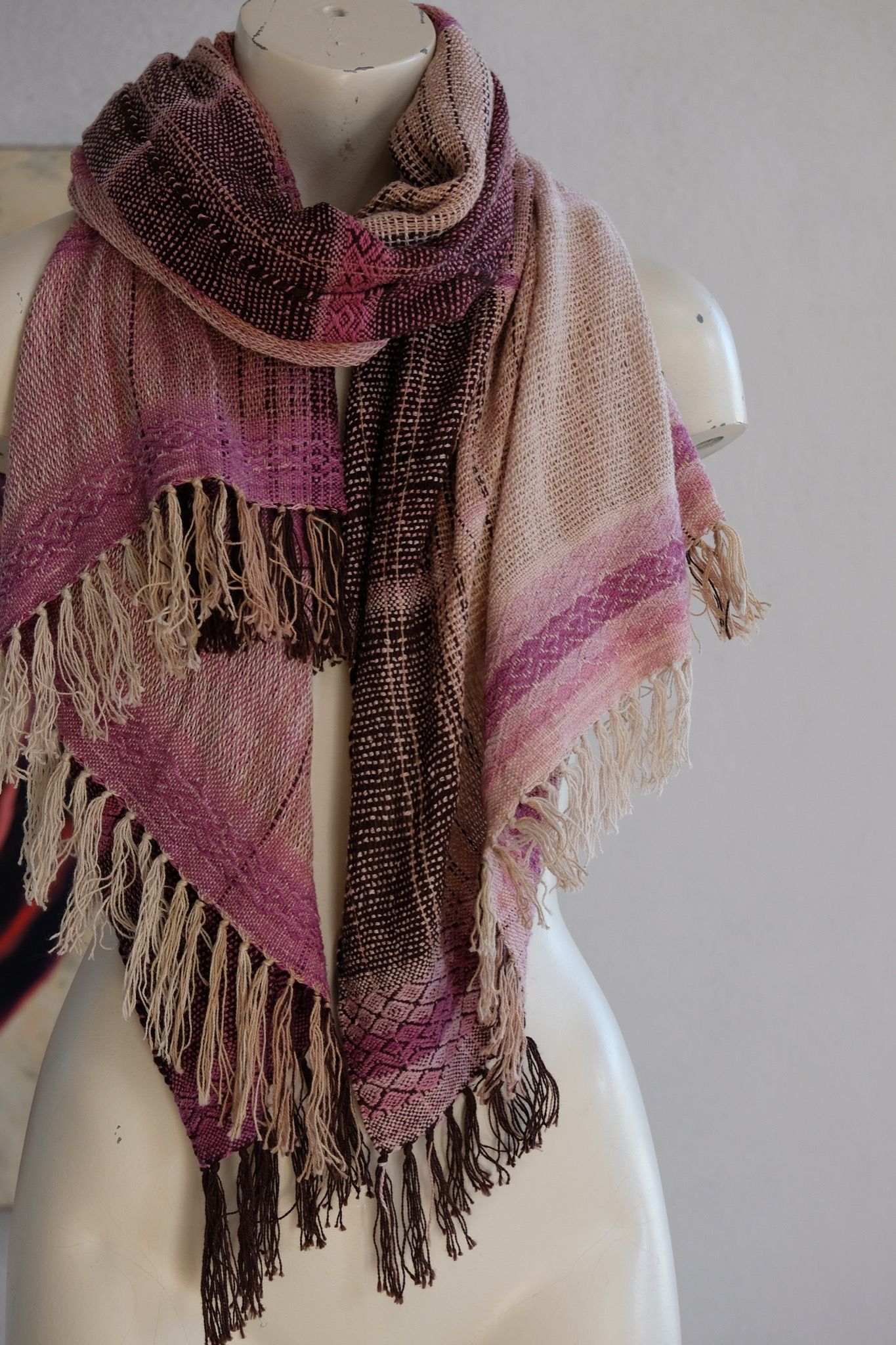 Handwoven scarf naturally dyed shades of pink and fuchsia on a white mannequin in a white gallery space