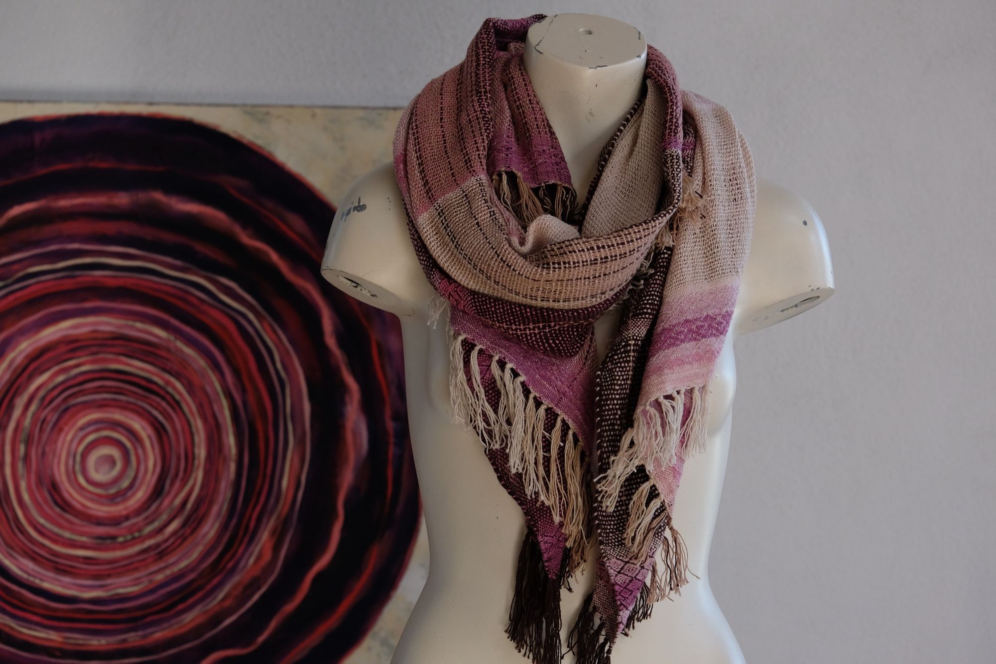 Handwoven scarf naturally dyed shades of pink and fuchsia on a white mannequin in a white gallery space