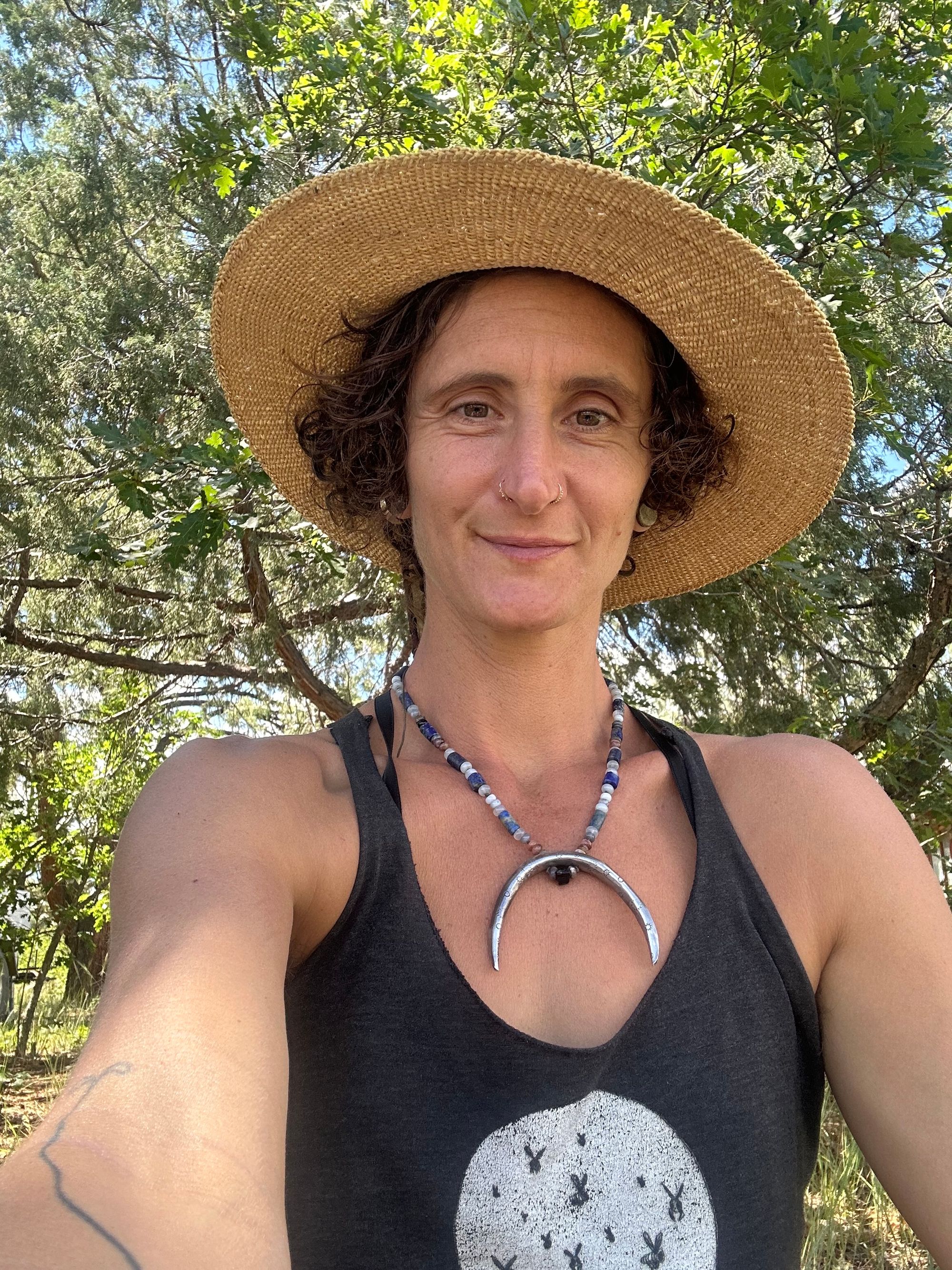 A woman wears a necklace with a sterling silver moon and semi precious stone beads, in the forest