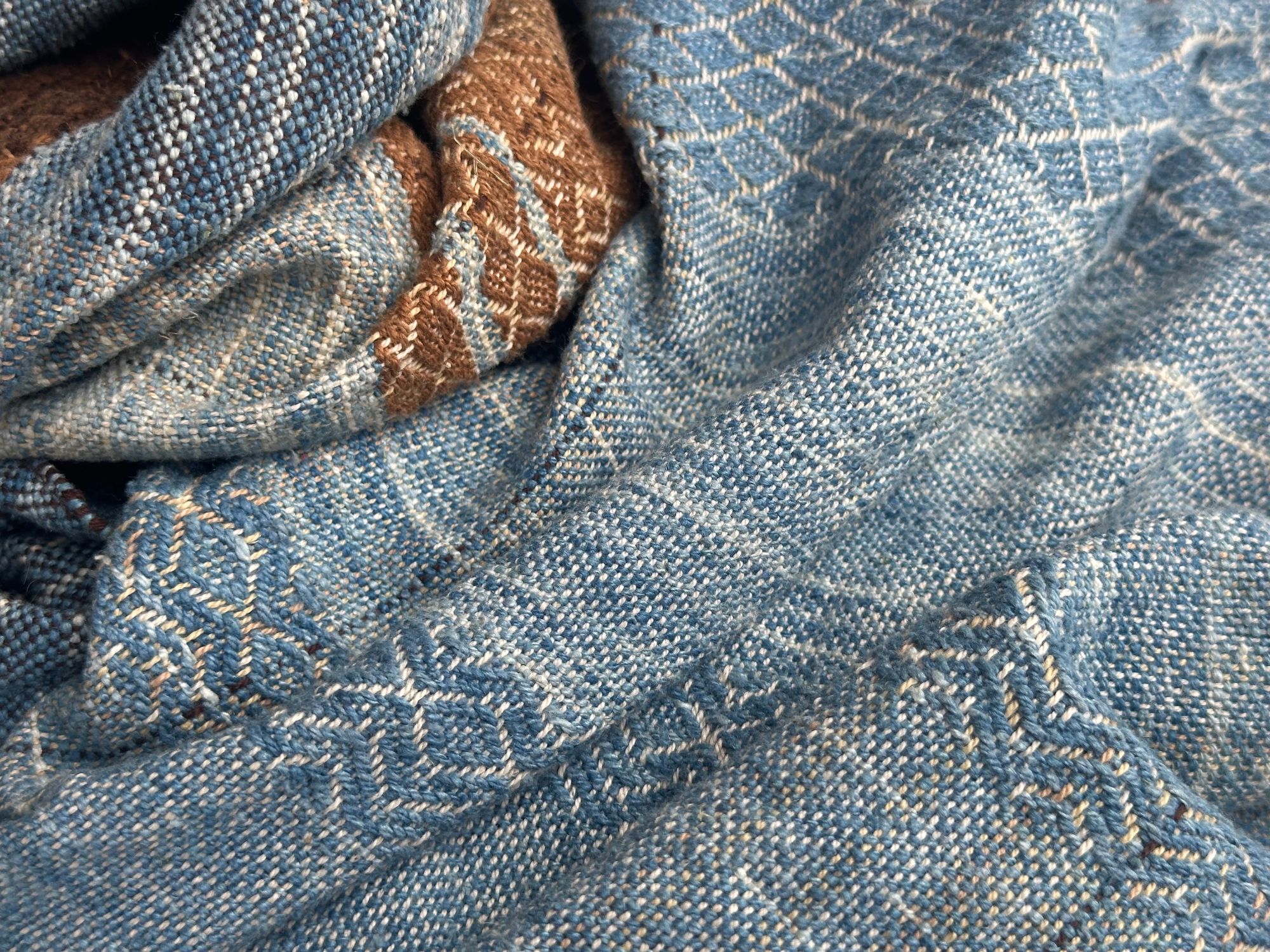 a 4.6 meter piece of handwoven fabric that is indigo blue and deep walnut dyed brown lays on a white floor