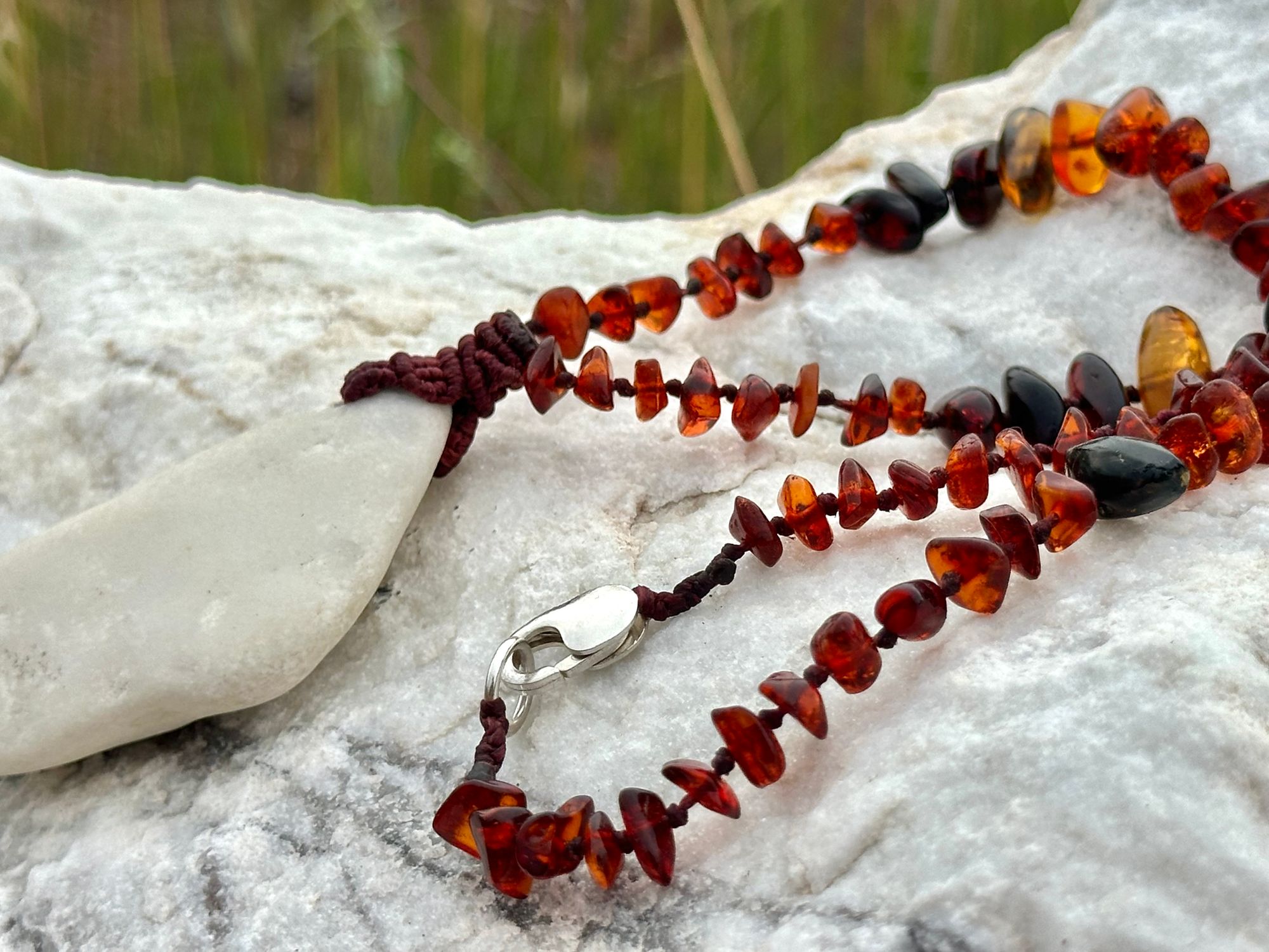 A necklace made of white river tumbled marble in a soft diamond shape is joined by beads of deep red orange Amber