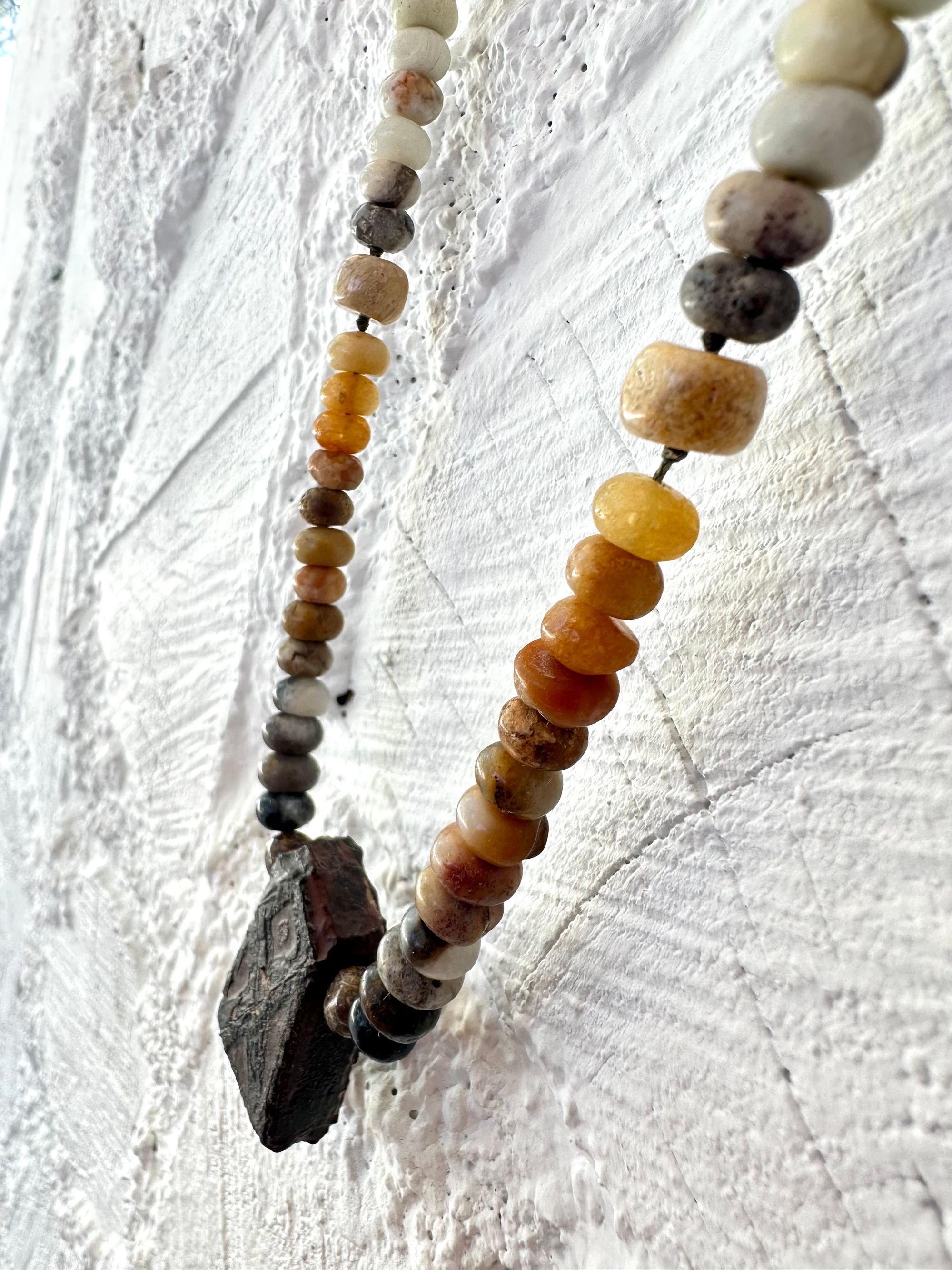 A necklace made of Gray, black and brown tsesit, A while, ancient stone is formed into an necklace with a rainbow of Jasper bees, petrified, dinosaur bone and fossilized coral