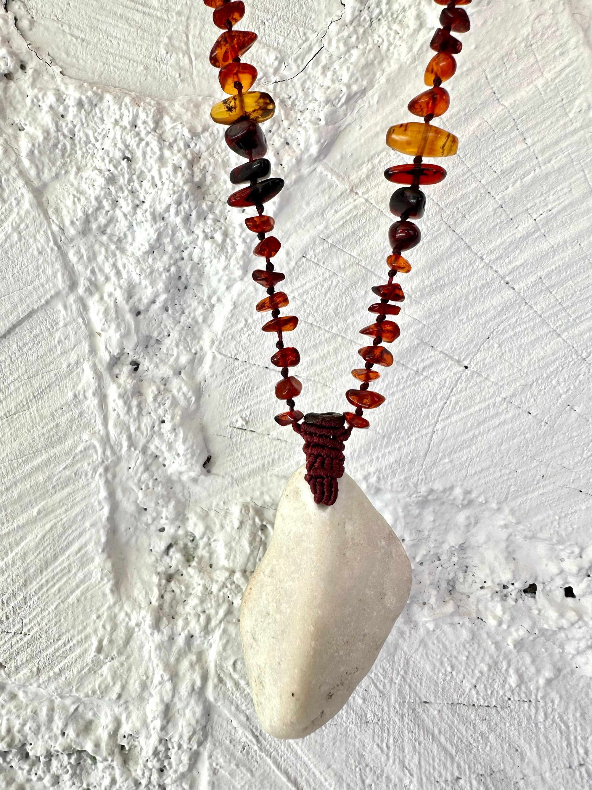 A necklace made of white river tumbled marble in a soft diamond shape is joined by beads of deep red orange Amber