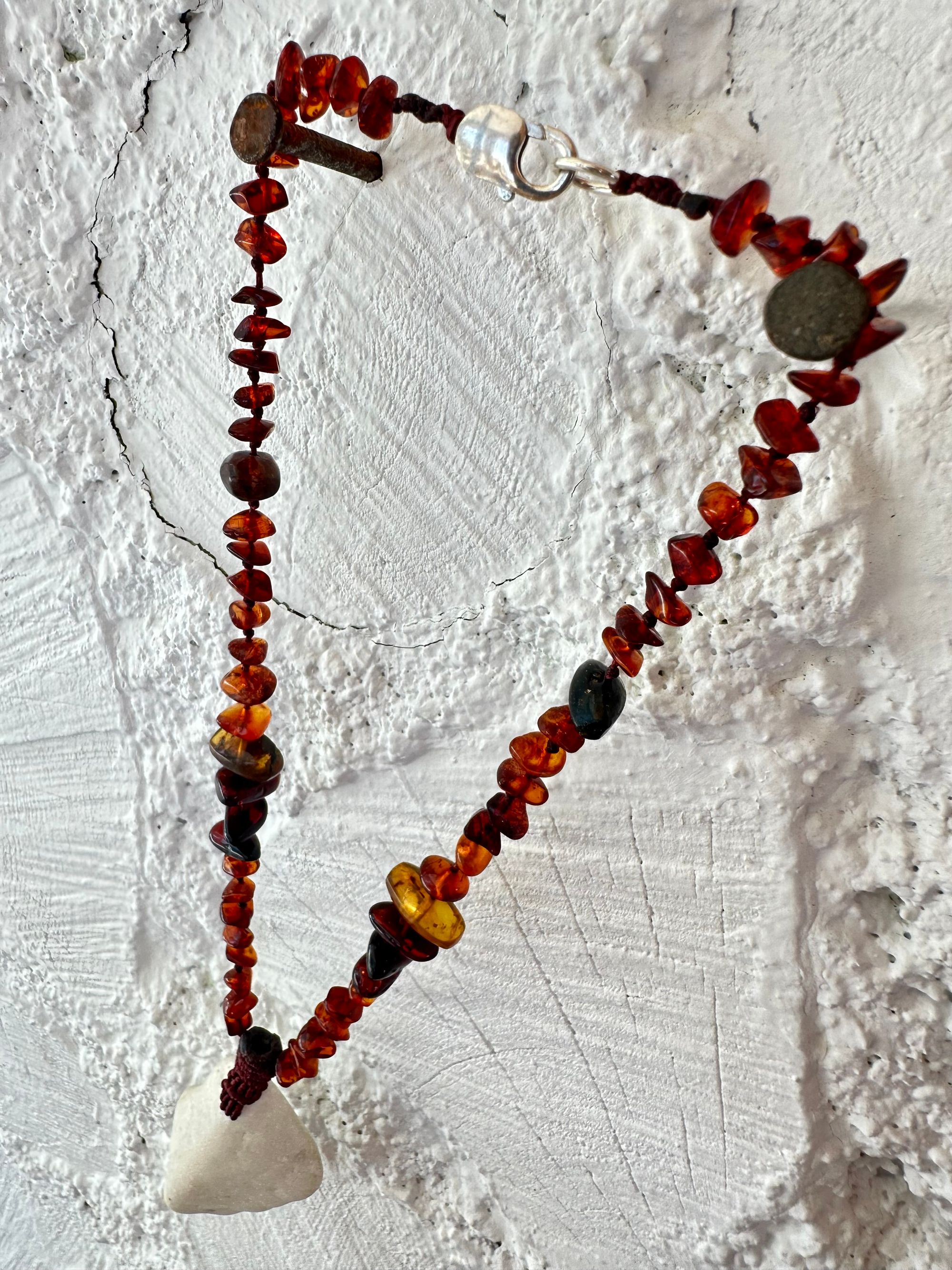 A necklace made of white river tumbled marble in a soft diamond shape is joined by beads of deep red orange Amber