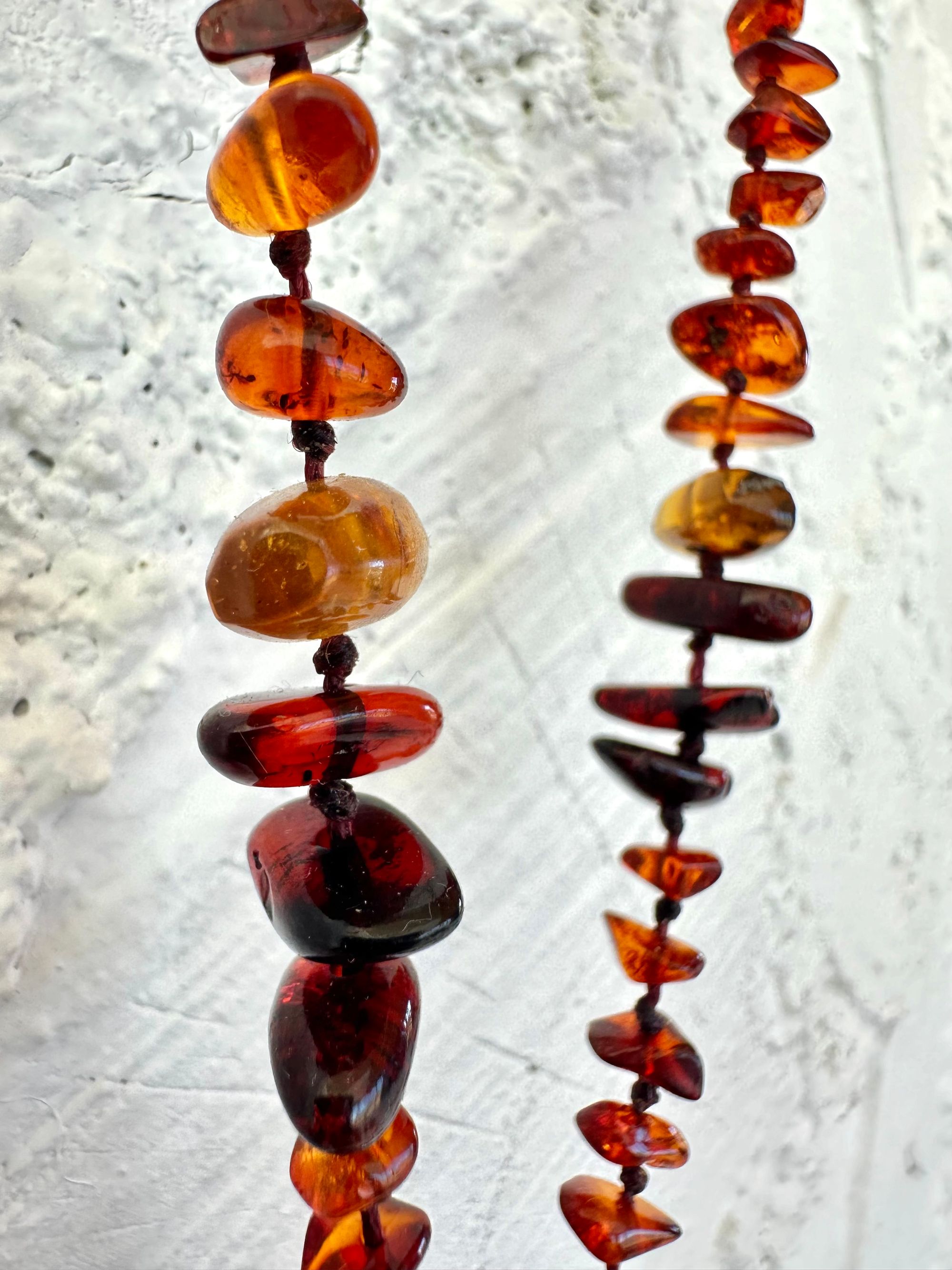 A necklace made of white river tumbled marble in a soft diamond shape is joined by beads of deep red orange Amber