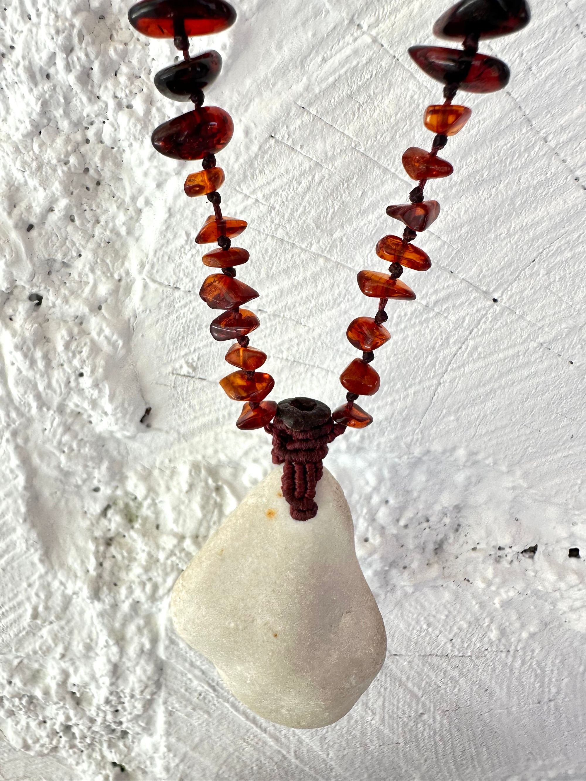 A necklace made of white river tumbled marble in a soft diamond shape is joined by beads of deep red orange Amber