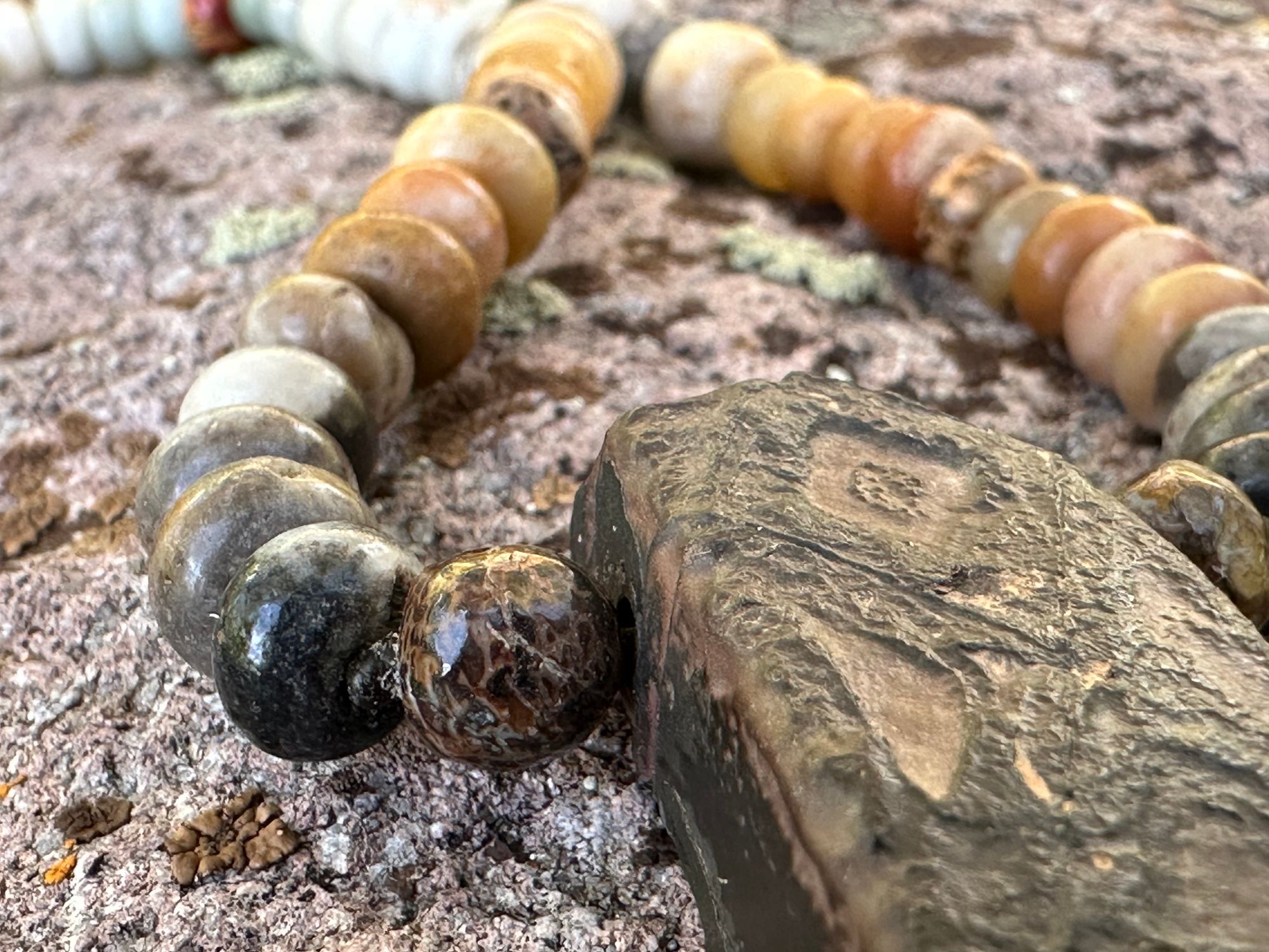 A detail of a necklace made of Tsesit, fossilized dinosaur bone, jasper, amazonite night and fossilized coral with a sterling silver clasp. 