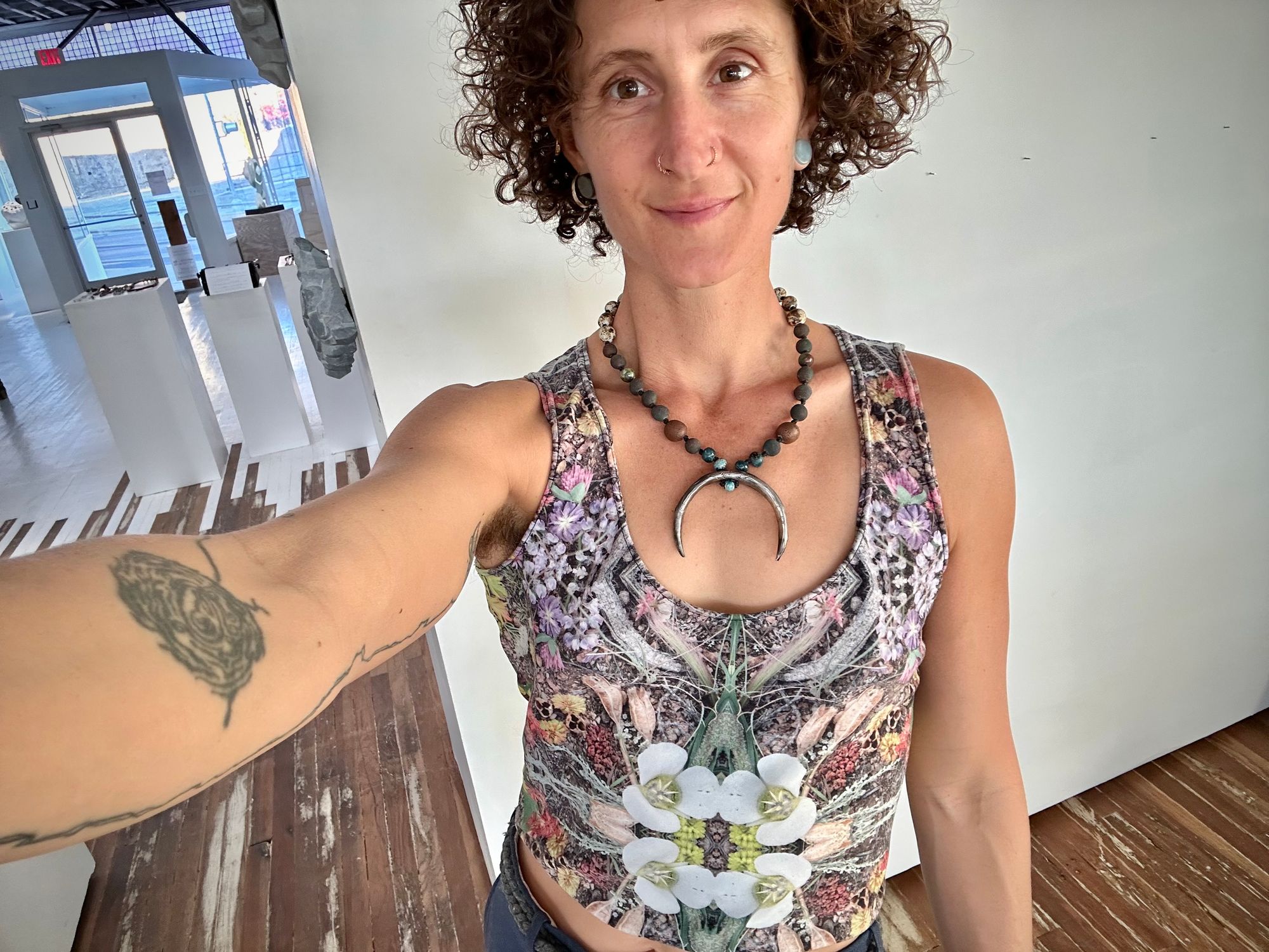 a woman in a floral print shirt wears a necklace with a sterling silver crescent moon and round clay beads