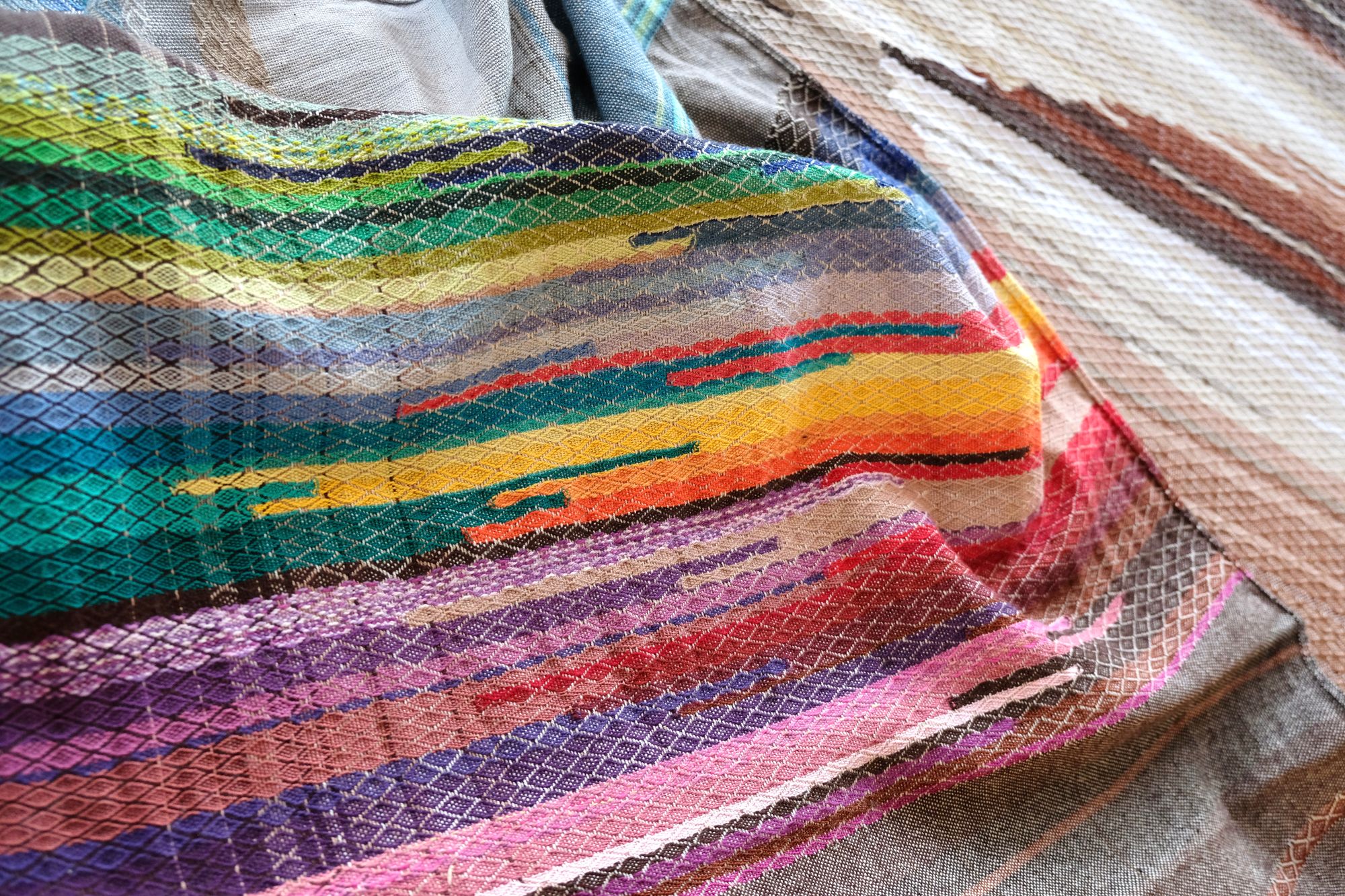 a detail of 5 m of head oven rainbow colored fabric layers on a wooden floor