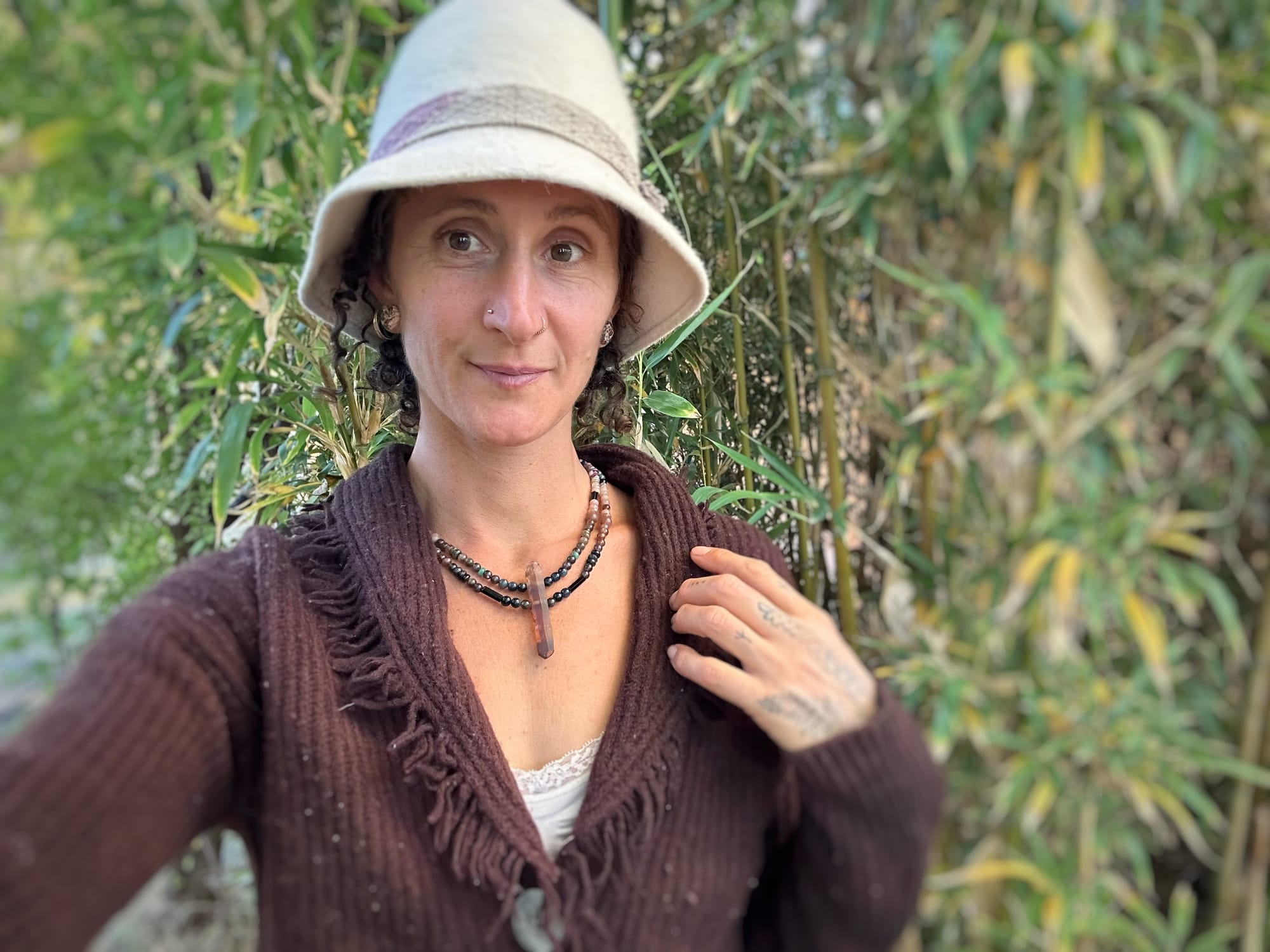 A citrine, cat's eye, tourmaline and emerald necklace by Jeannie OrtizA woman wears a crystal and stone necklace as well as a wooly brown sweater and white wool hat
