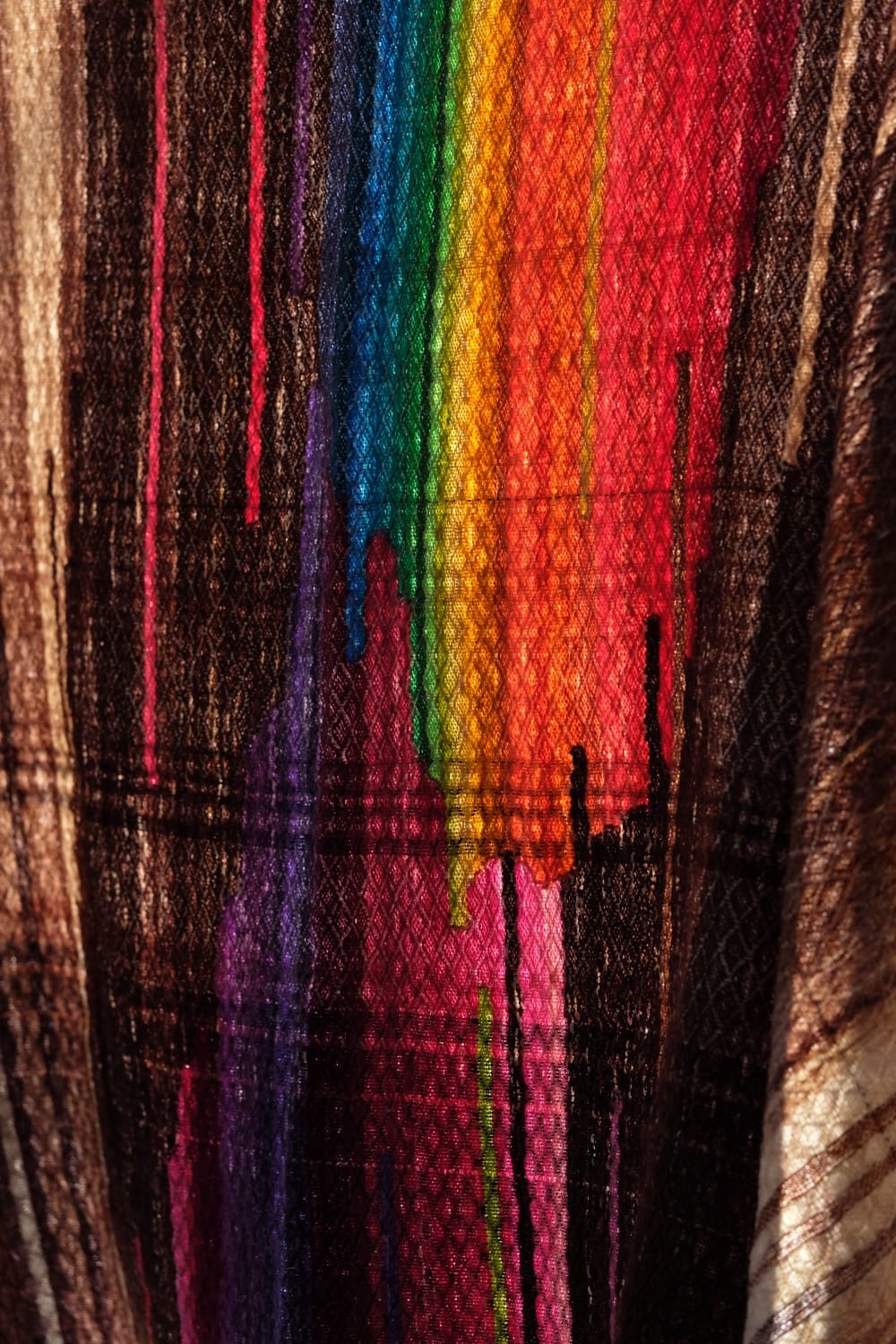 A length of handwoven fabric with details of fluid rainbows, a blue illuminated river and snowflakes