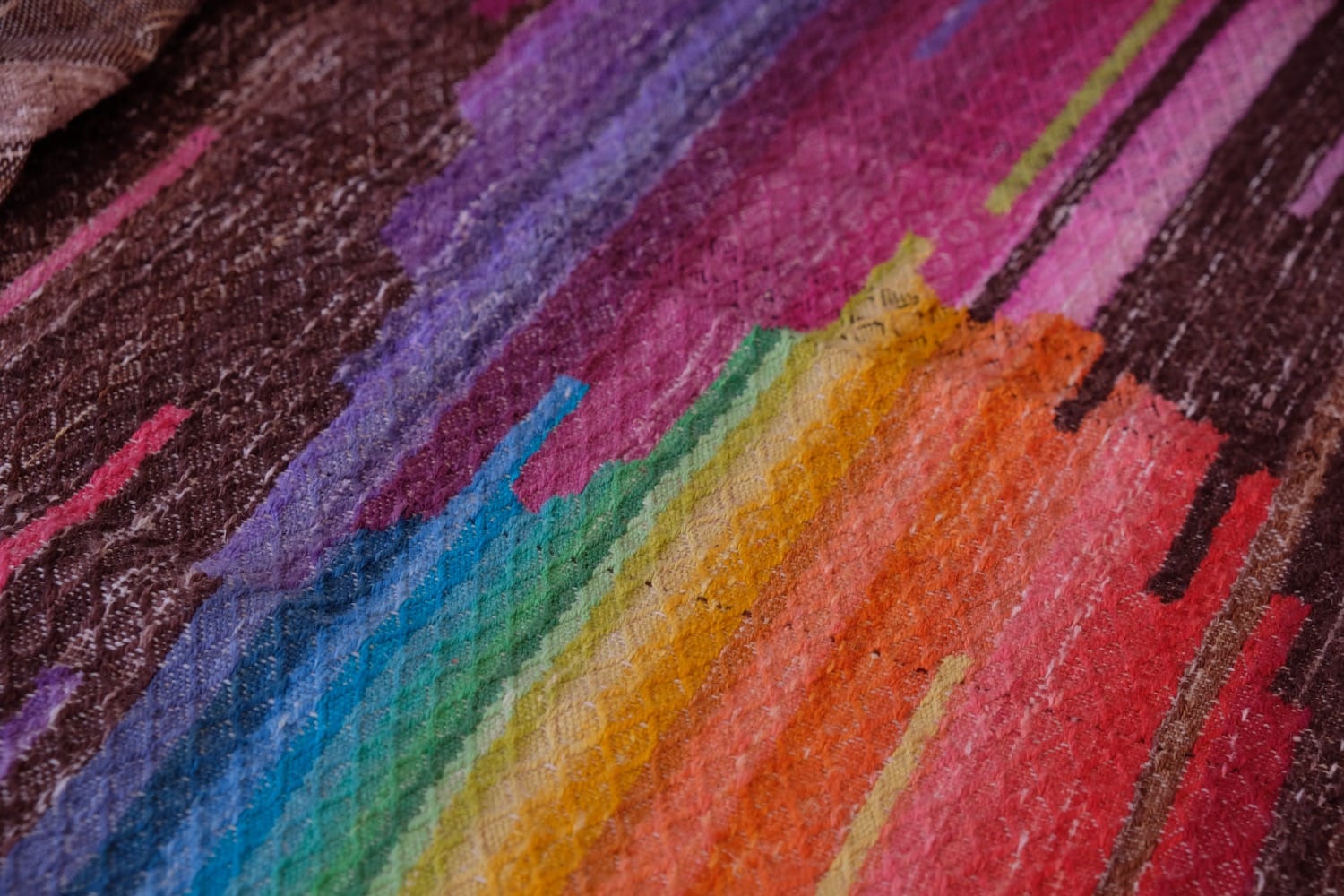 A length of handwoven fabric with details of fluid rainbows, a blue illuminated river and snowflakes