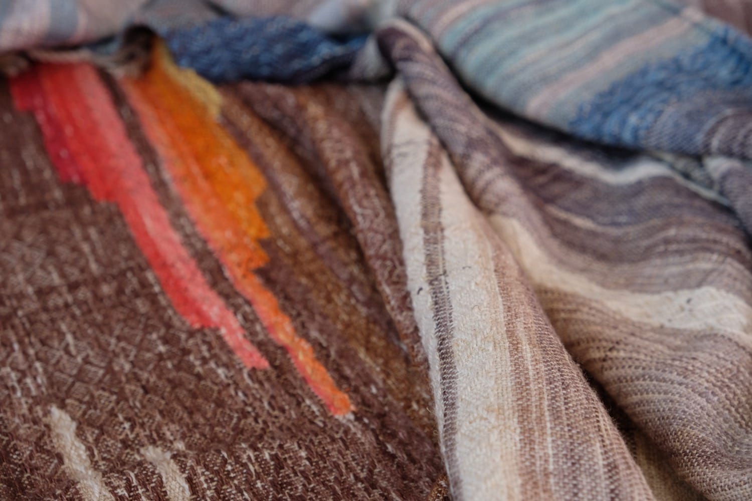 A length of handwoven fabric with details of fluid rainbows, a blue illuminated river and snowflakes