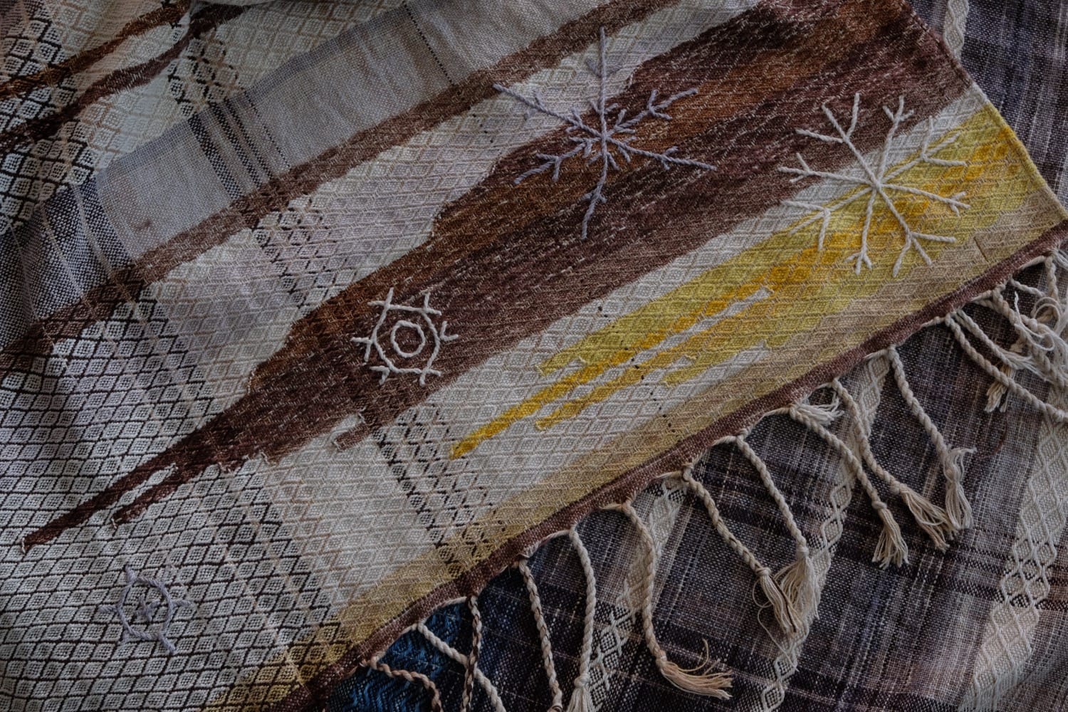 A length of handwoven fabric with details of fluid rainbows, a blue illuminated river and snowflakes