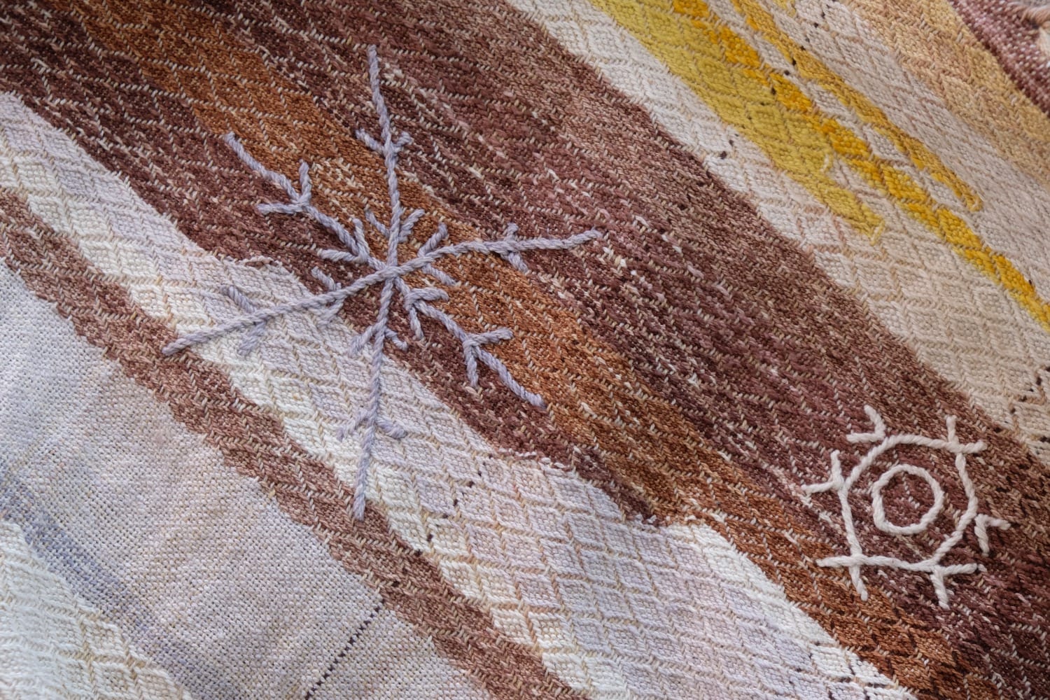 A length of handwoven fabric with details of fluid rainbows, a blue illuminated river and snowflakes