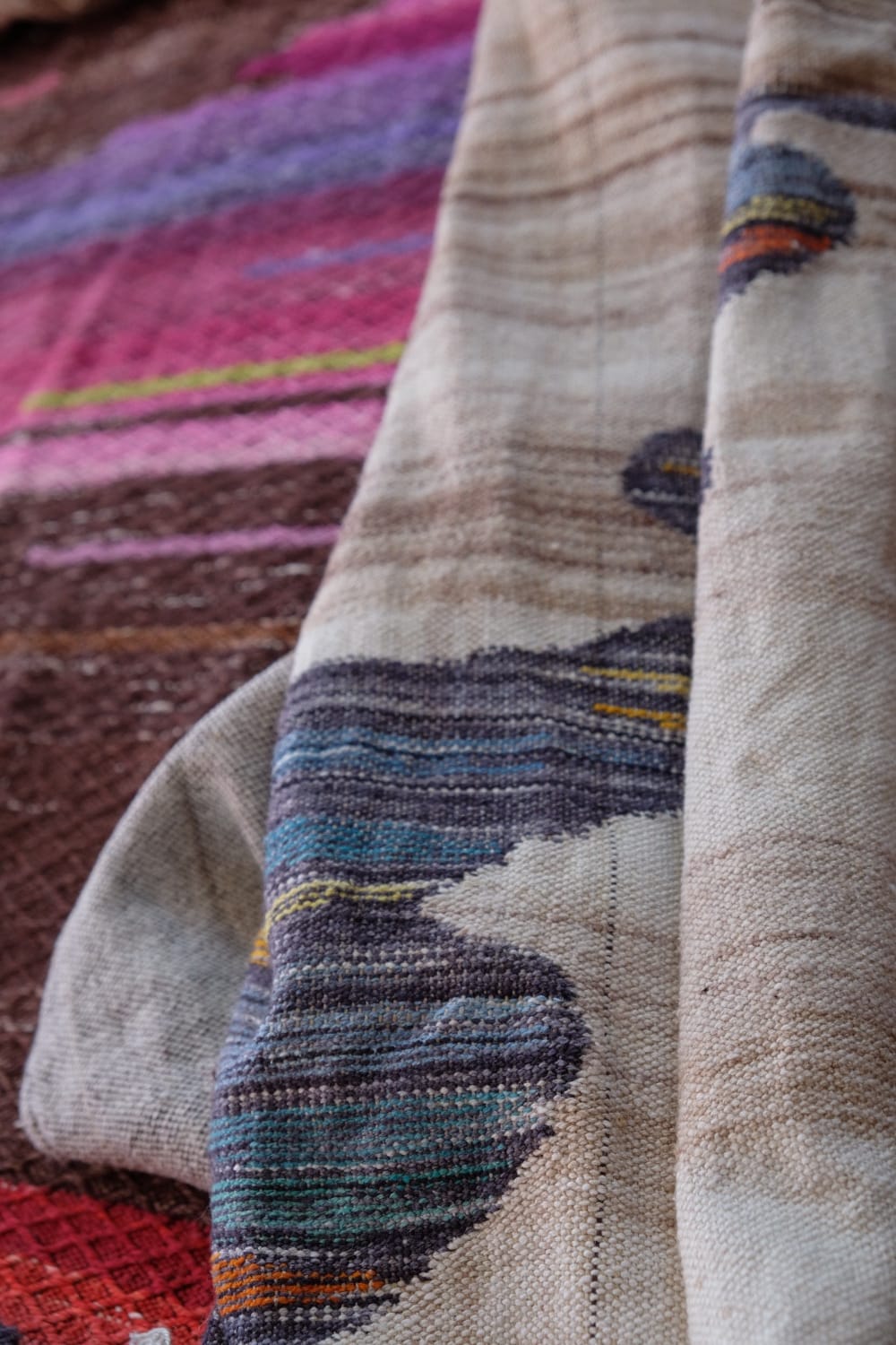 A length of handwoven fabric with details of fluid rainbows, a blue illuminated river and snowflakes