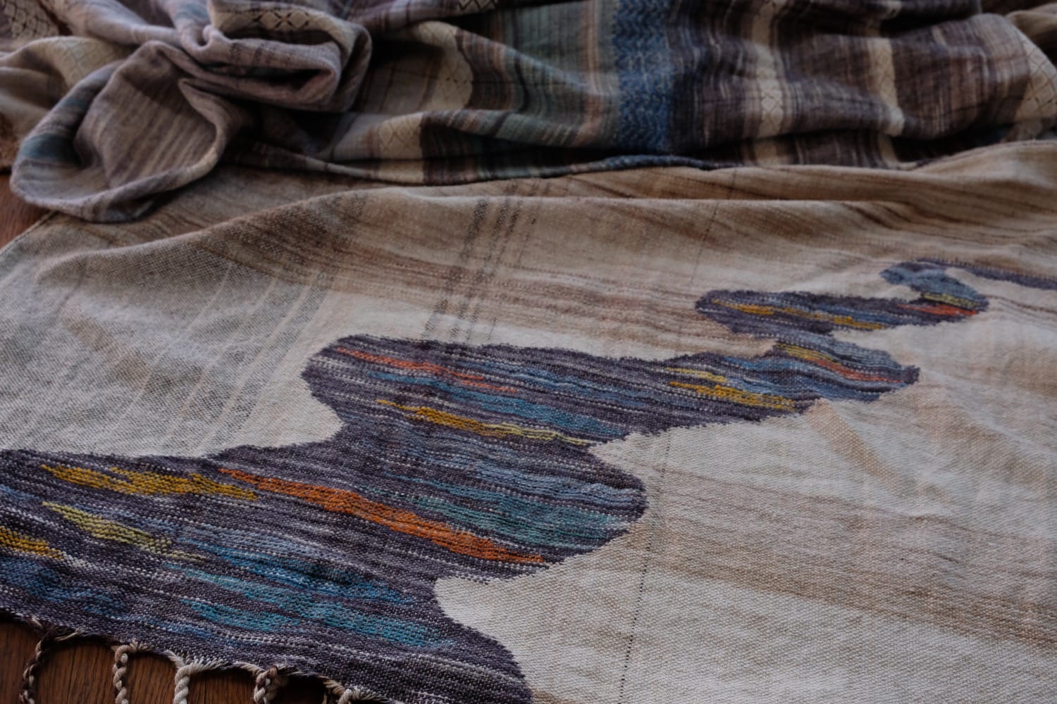A length of handwoven fabric with details of fluid rainbows, a blue illuminated river and snowflakes