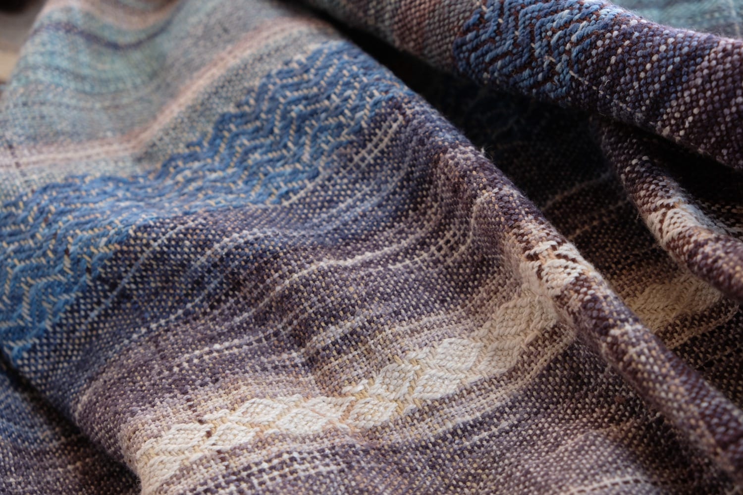 A length of handwoven fabric with details of fluid rainbows, a blue illuminated river and snowflakes
