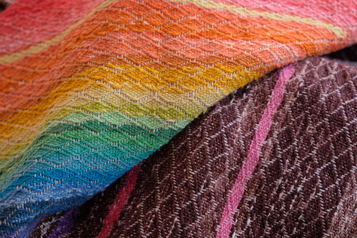 A length of handwoven fabric with details of fluid rainbows, a blue illuminated river and snowflakes