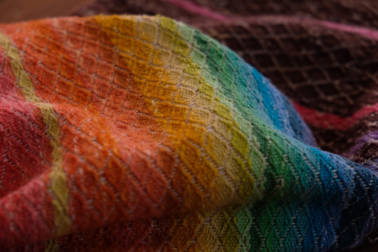 A length of handwoven fabric with details of fluid rainbows, a blue illuminated river and snowflakes