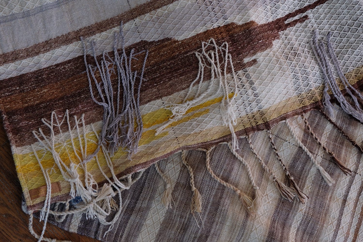 A length of handwoven fabric with details of fluid rainbows, a blue illuminated river and snowflakes