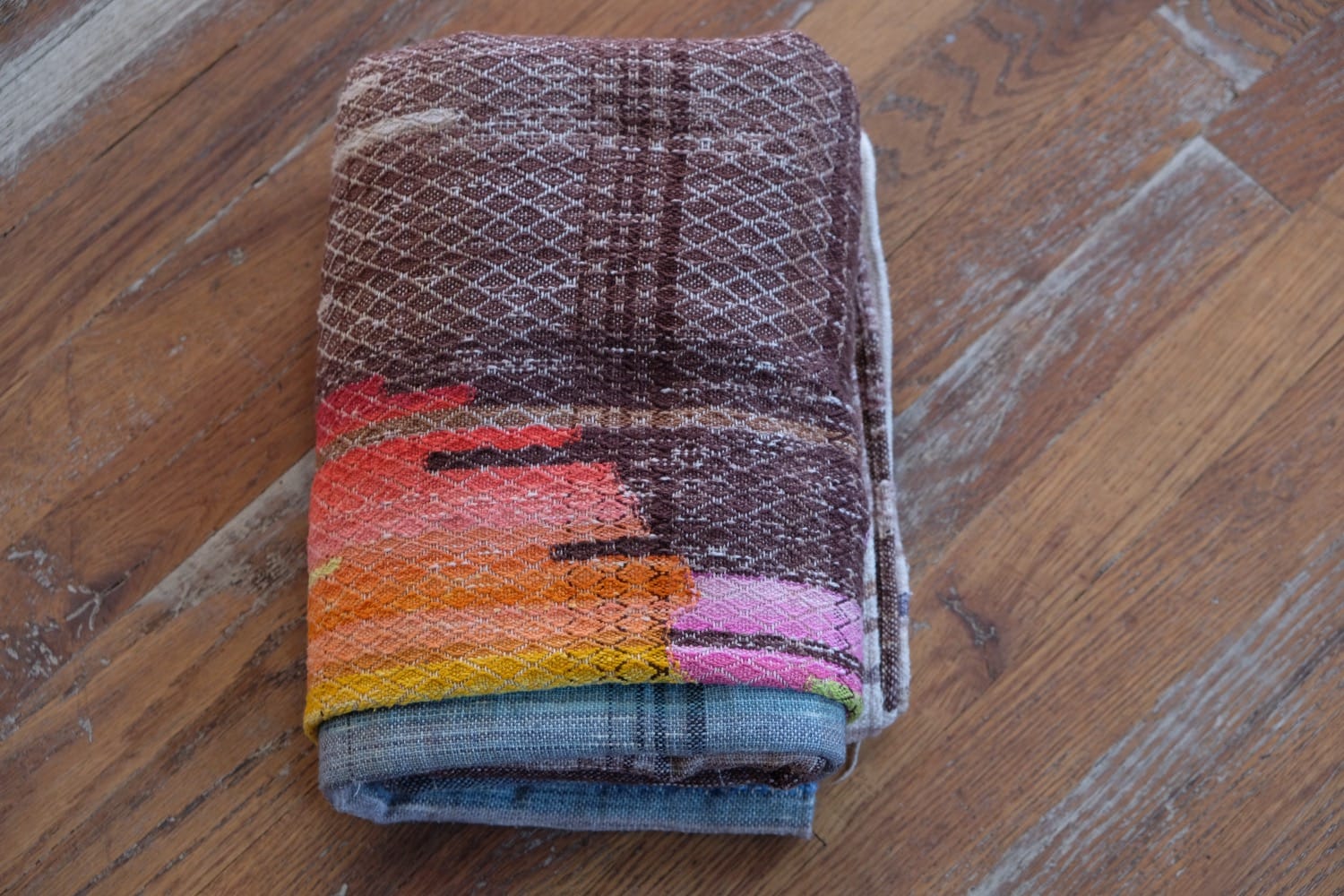 A length of handwoven fabric with details of fluid rainbows, a blue illuminated river and snowflakes