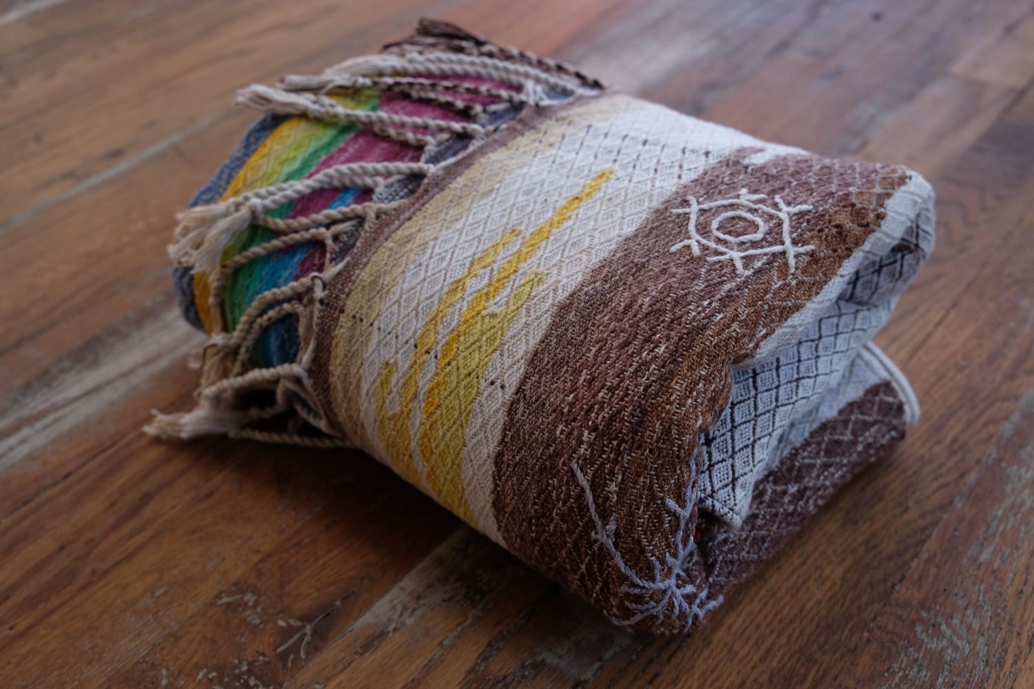 A length of handwoven fabric with details of fluid rainbows, a blue illuminated river and snowflakes