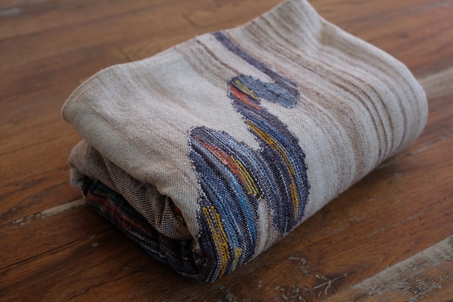 A length of handwoven fabric with details of fluid rainbows, a blue illuminated river and snowflakes