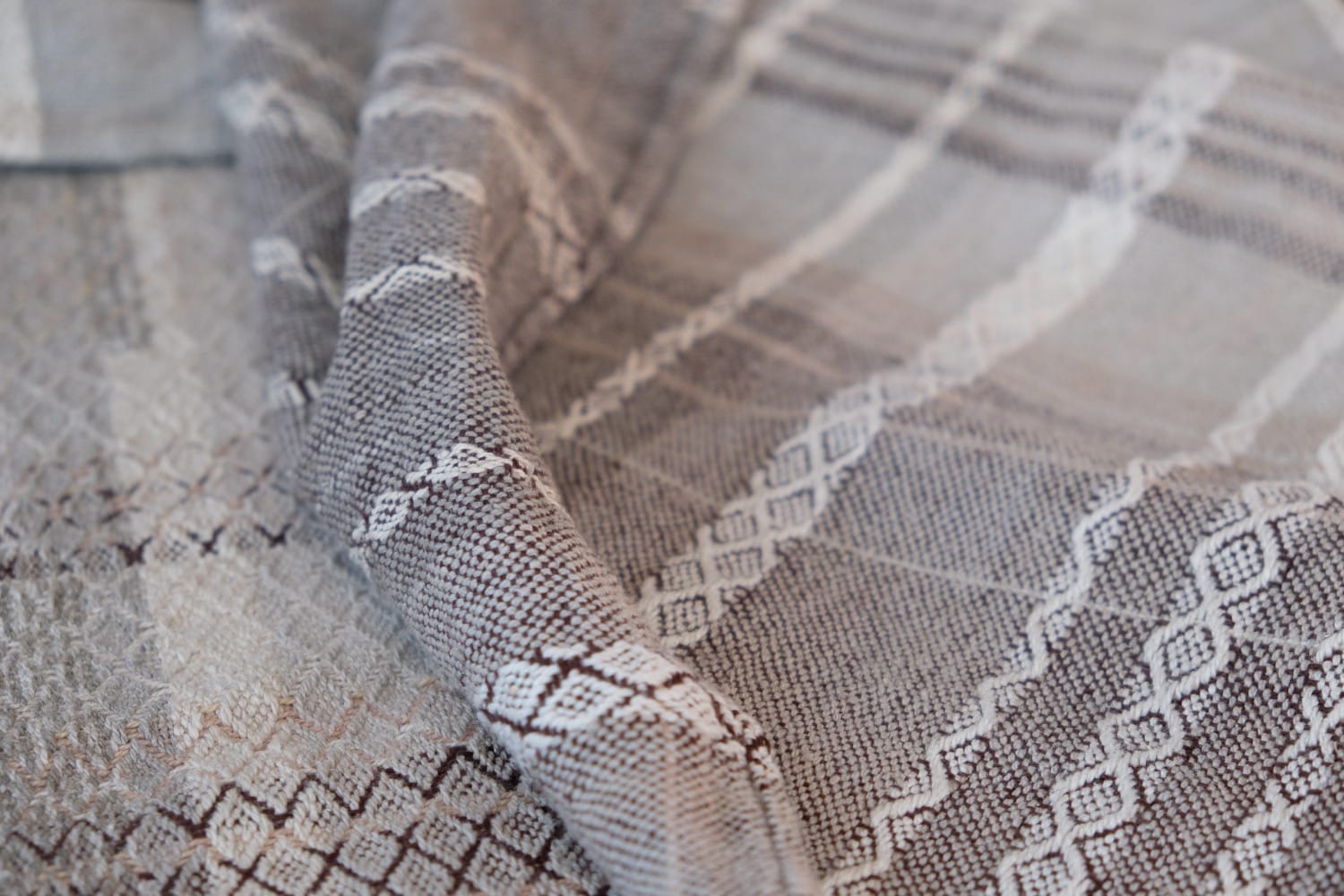 A detail of naturally dyed handwoven fabric in moody shades of gray, misty blue and black with a white moon in the middle and cloud designs throughout